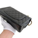 Charger l&#39;image dans la galerie, Black quilted handbag held by a gloved hand on a white background
