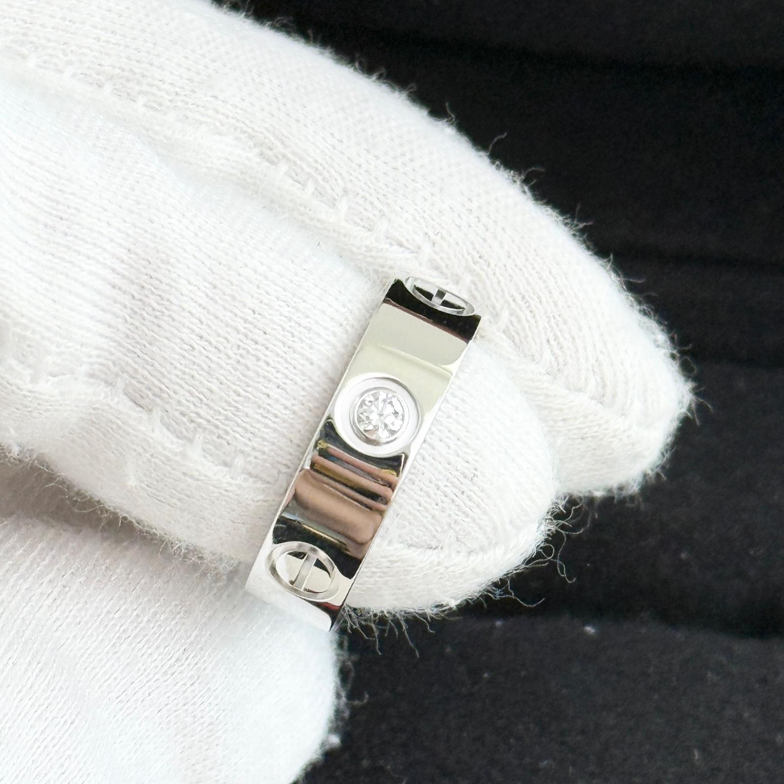 Close-up of a silver ring with a logo on a white fabric background