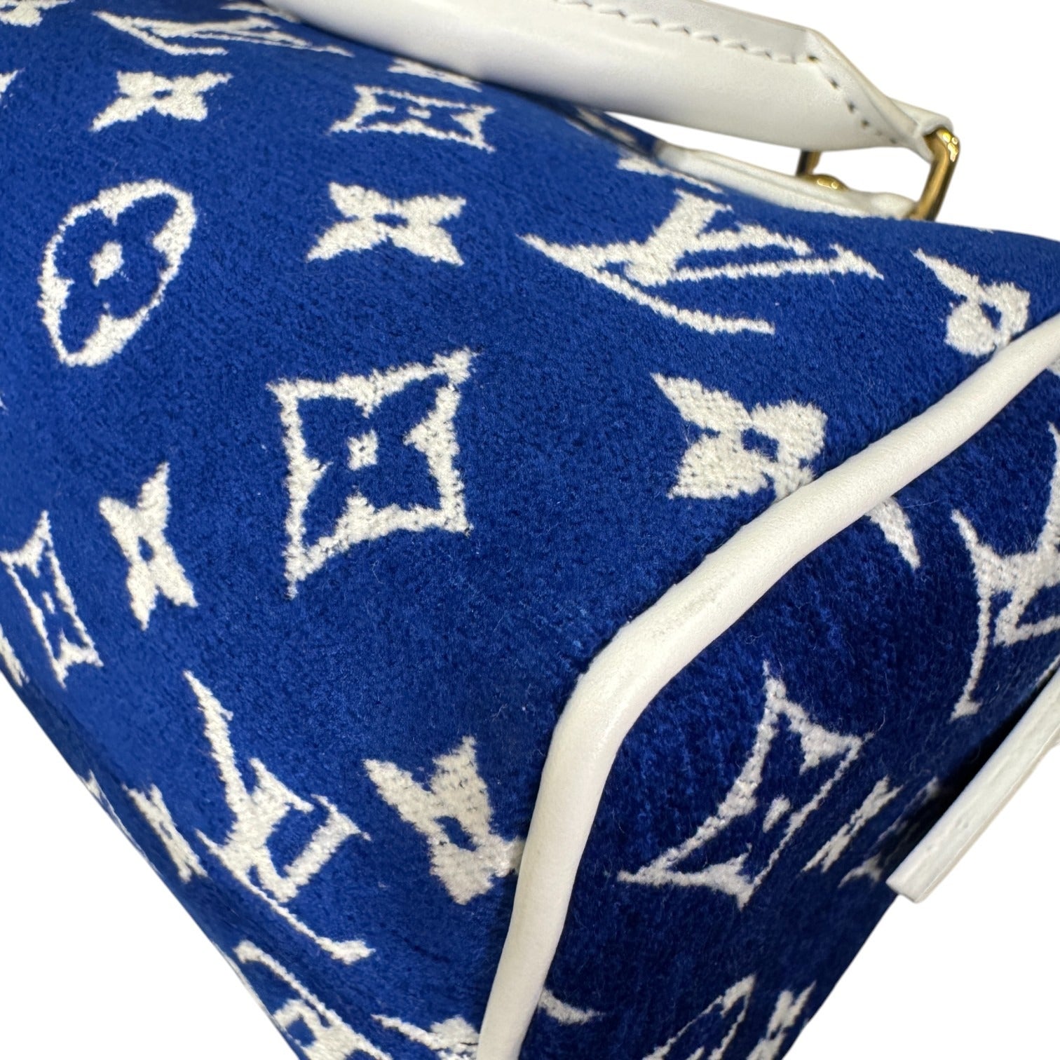 Blue handbag with white monogram pattern on a white background