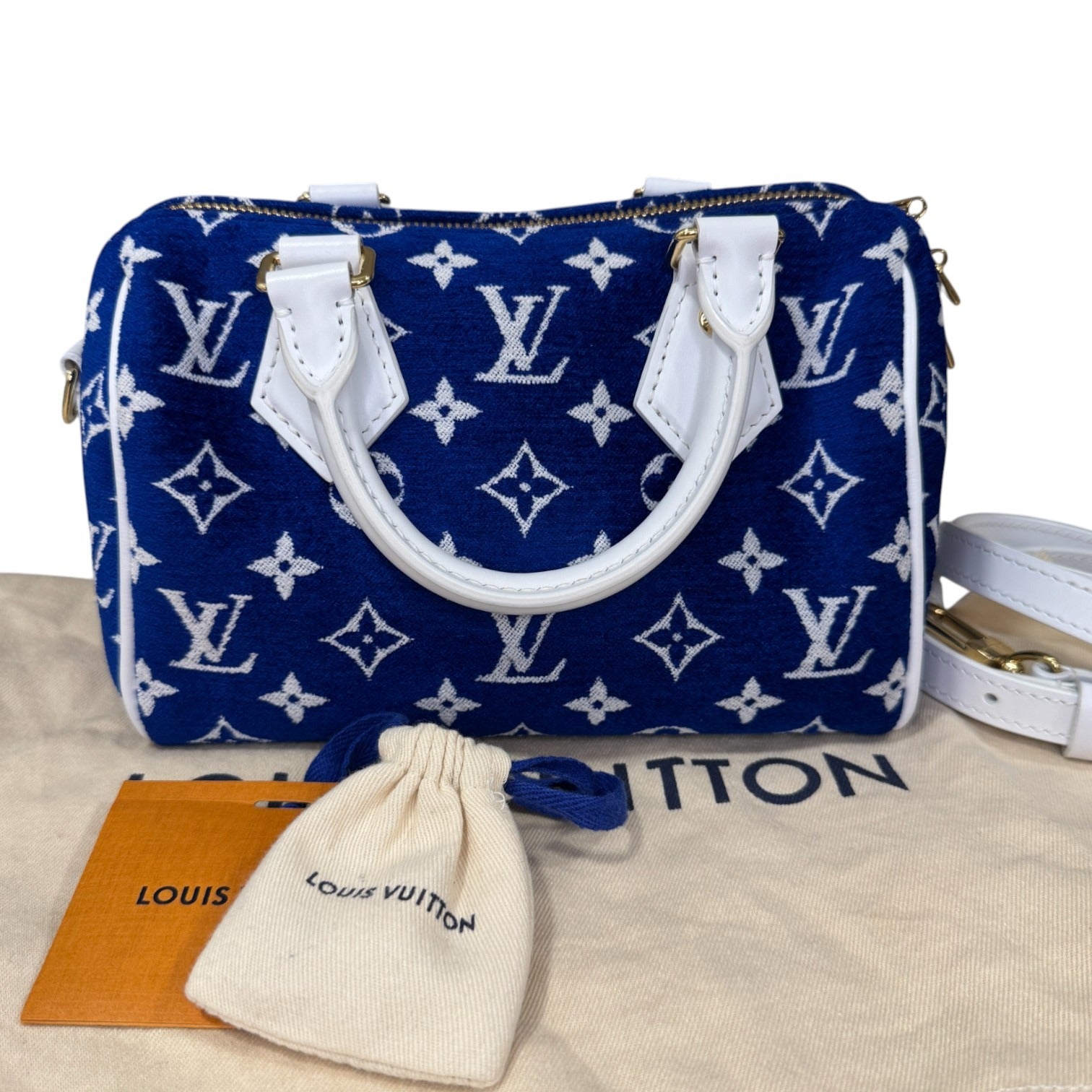 Blue handbag with white monogram pattern on a beige surface with Louis Vuitton packaging.