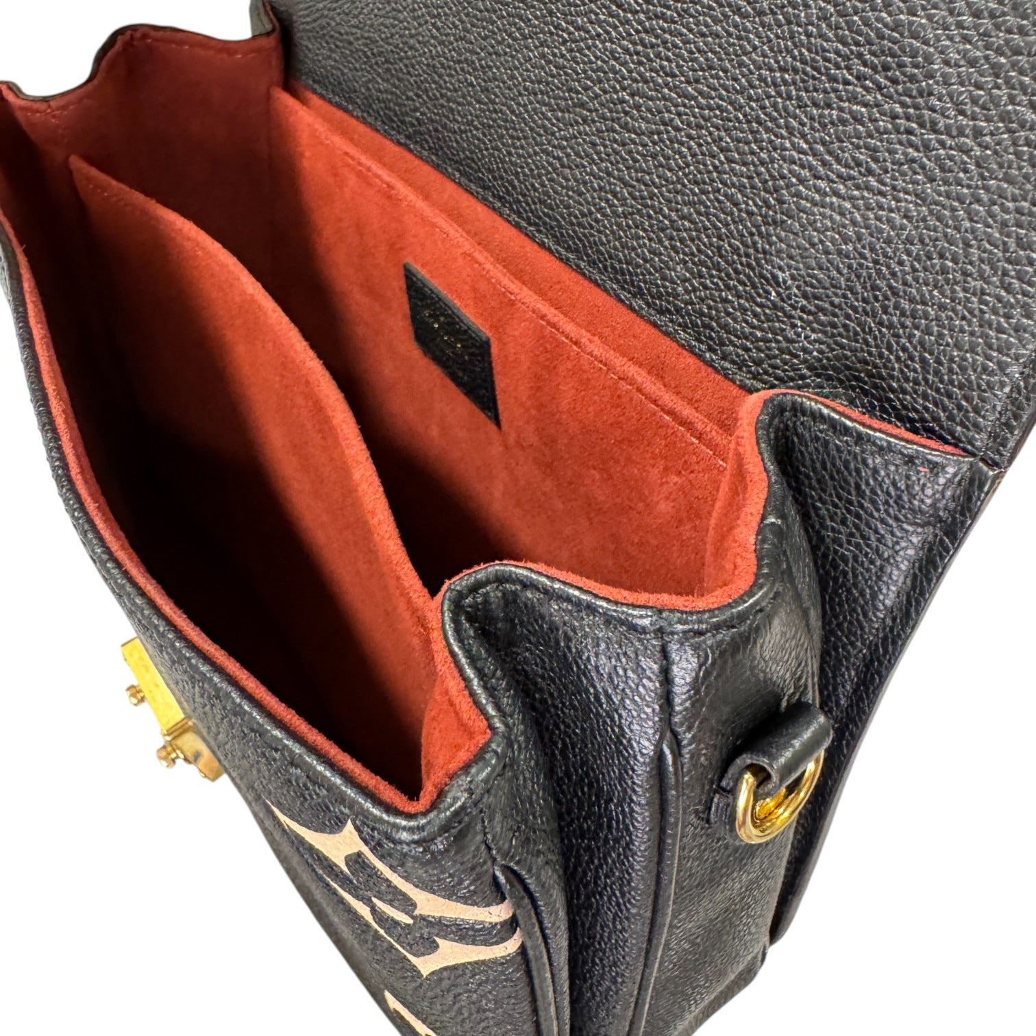 Close-up of a black leather handbag with red interior lining and gold accents.