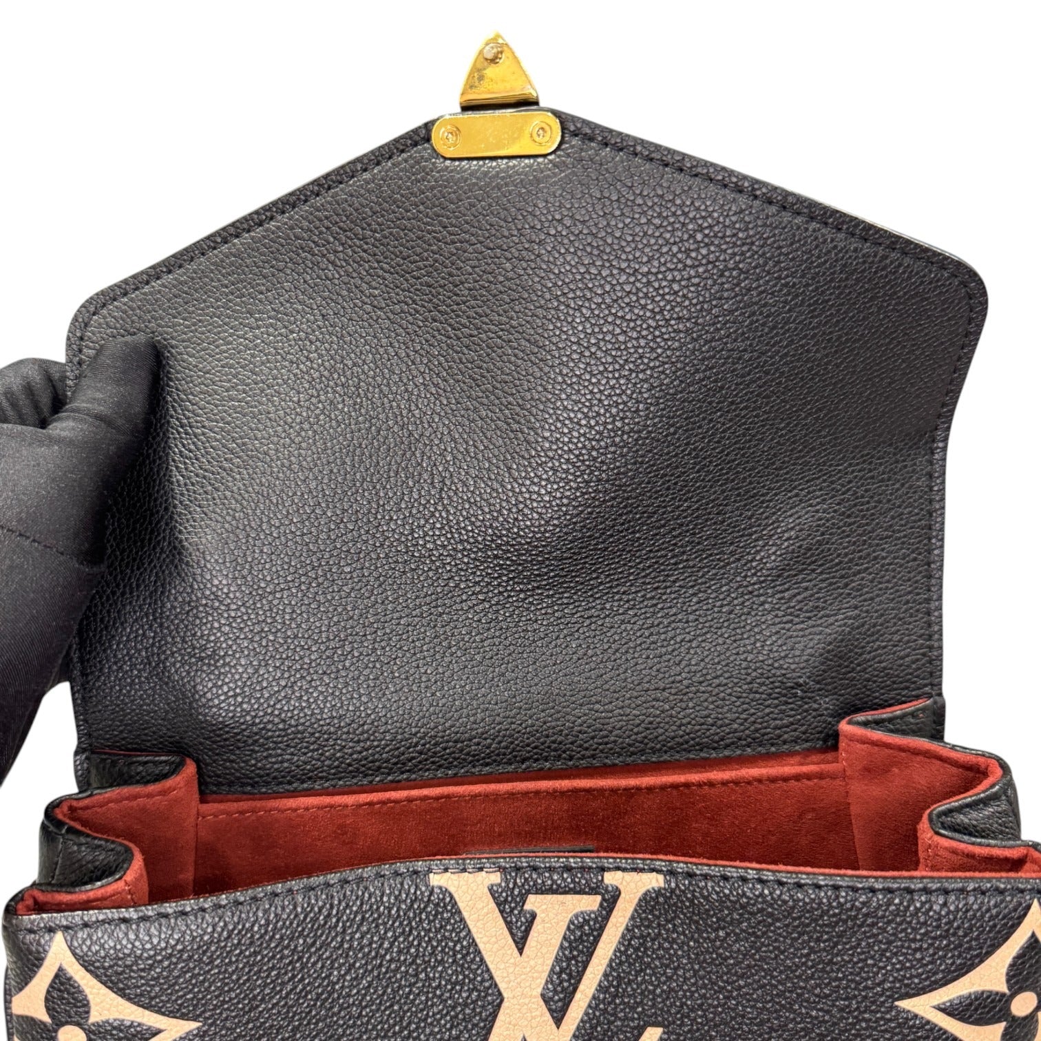 Close-up of a black leather handbag with gold accents, featuring the Louis Vuitton logo.