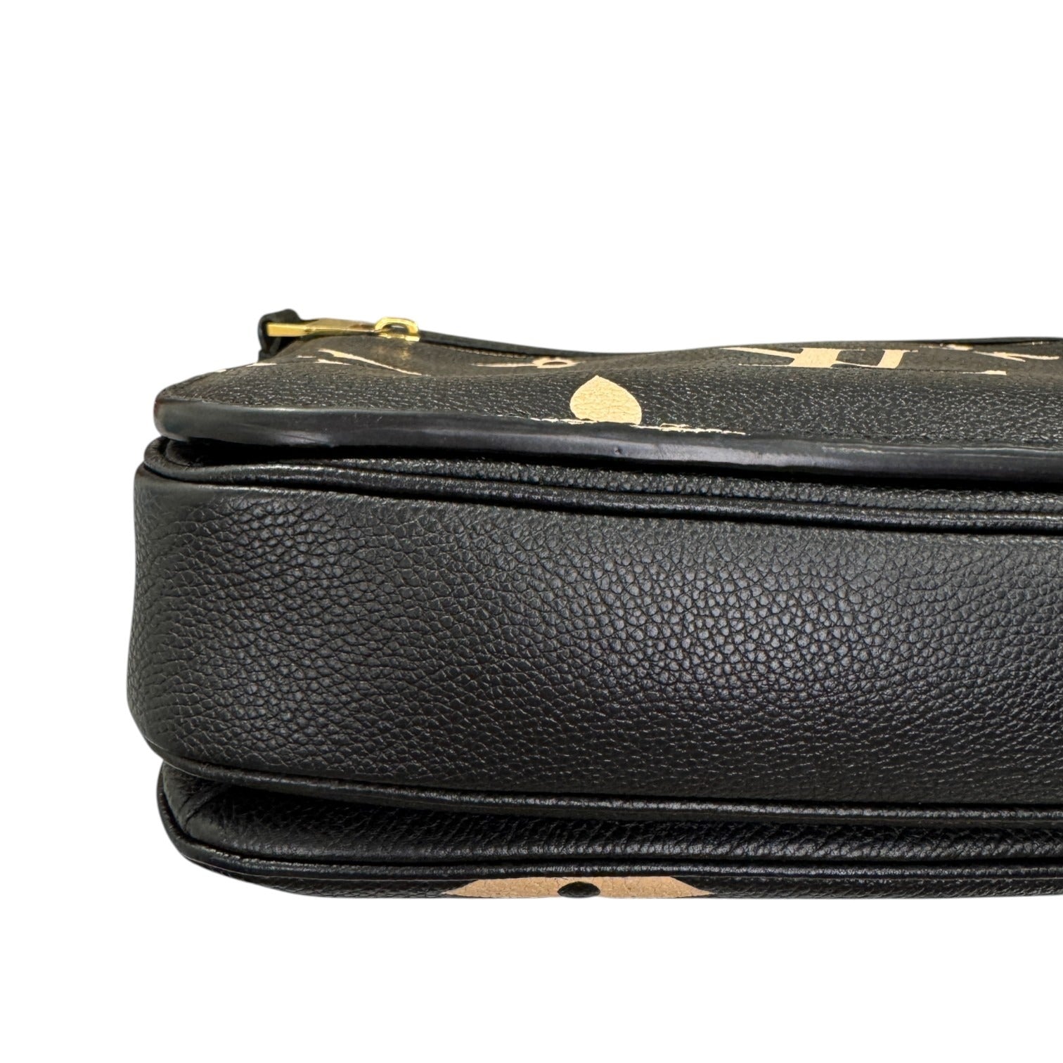 Close-up of a black leather handbag with gold accents on a white background