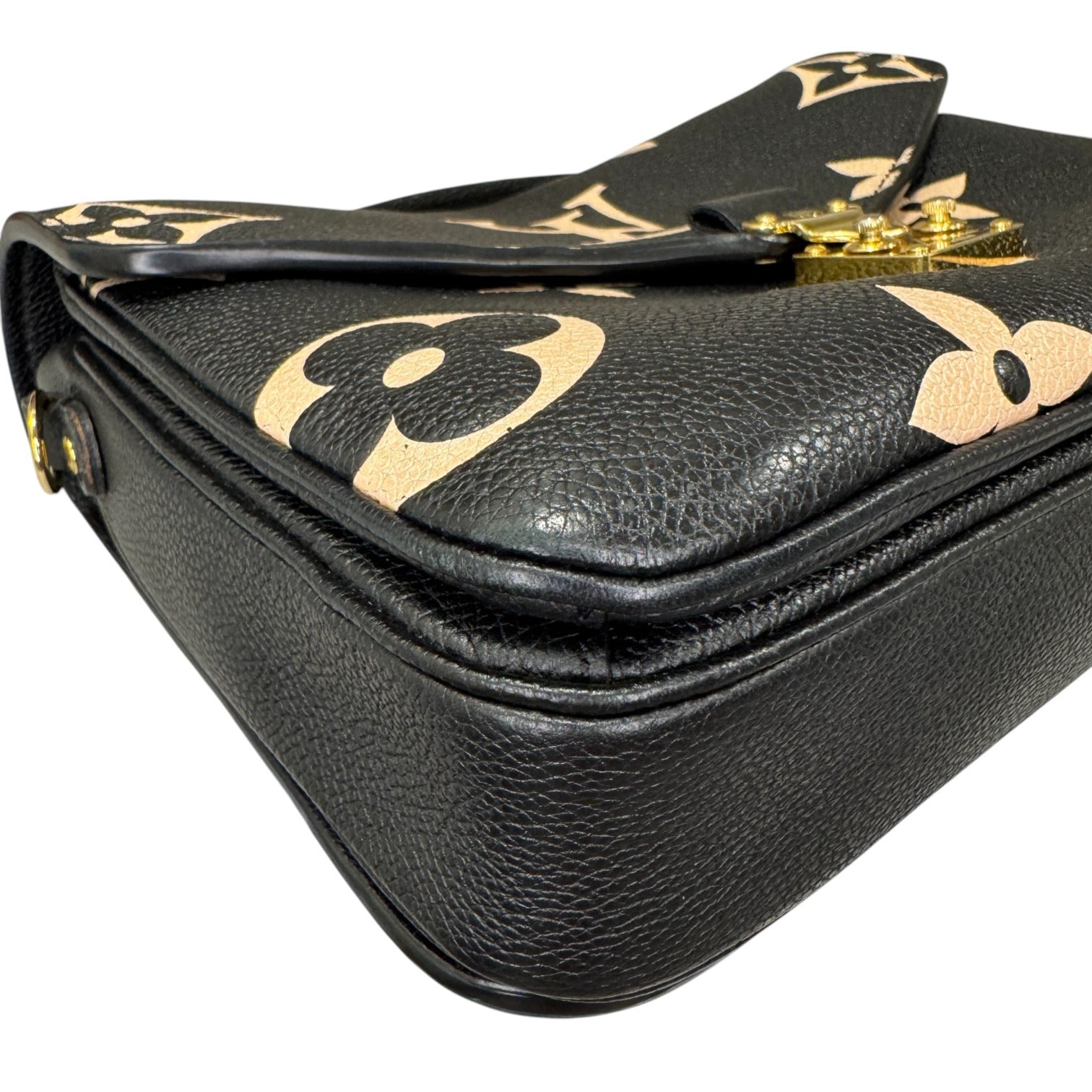 Black leather handbag with gold floral patterns on a white background