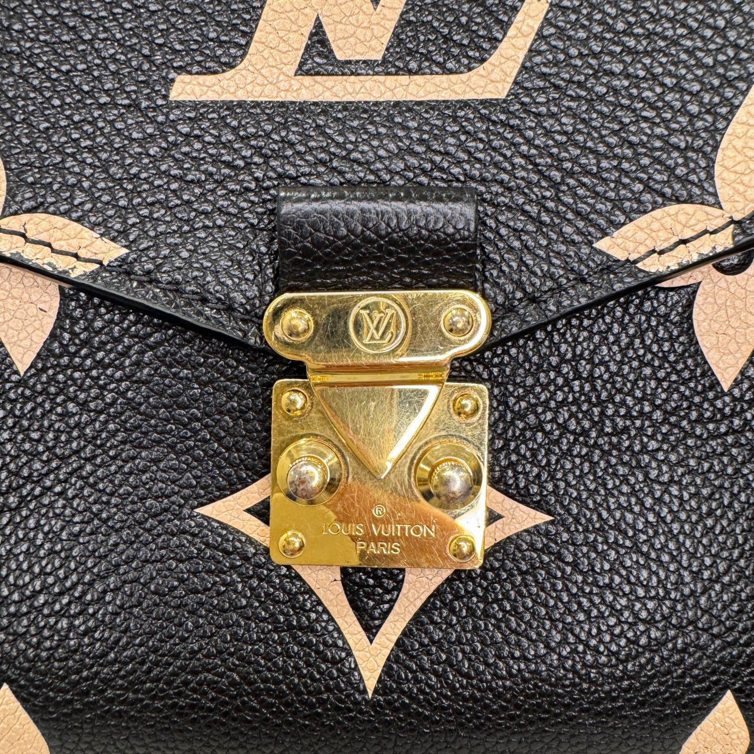 Close-up of a Louis Vuitton handbag with gold hardware and monogram pattern.