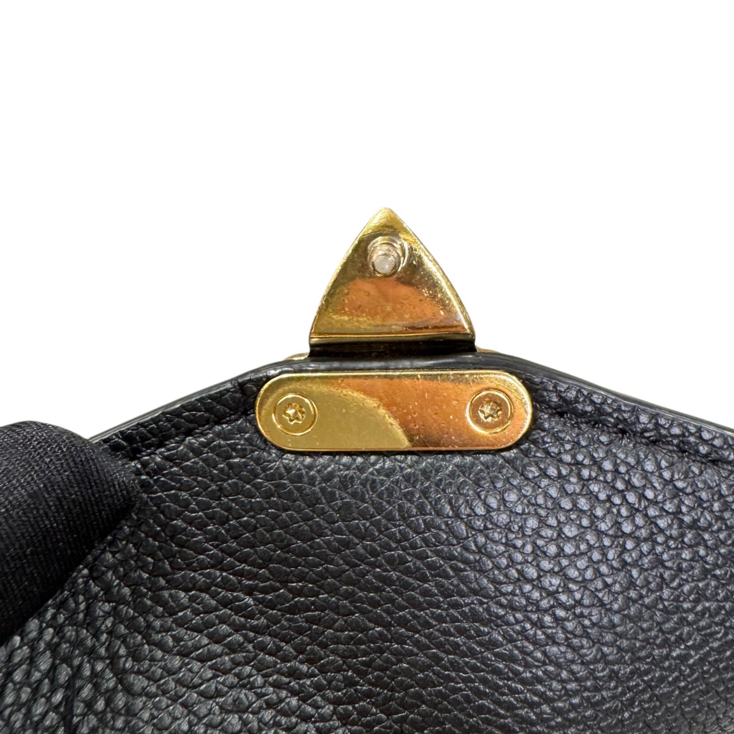 Close-up of a black leather bag with gold hardware on a white background