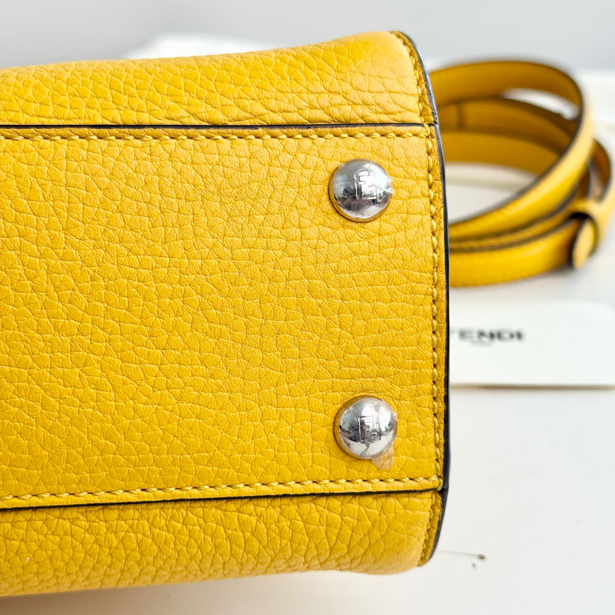 Yellow leather handbag with silver studs on a light background