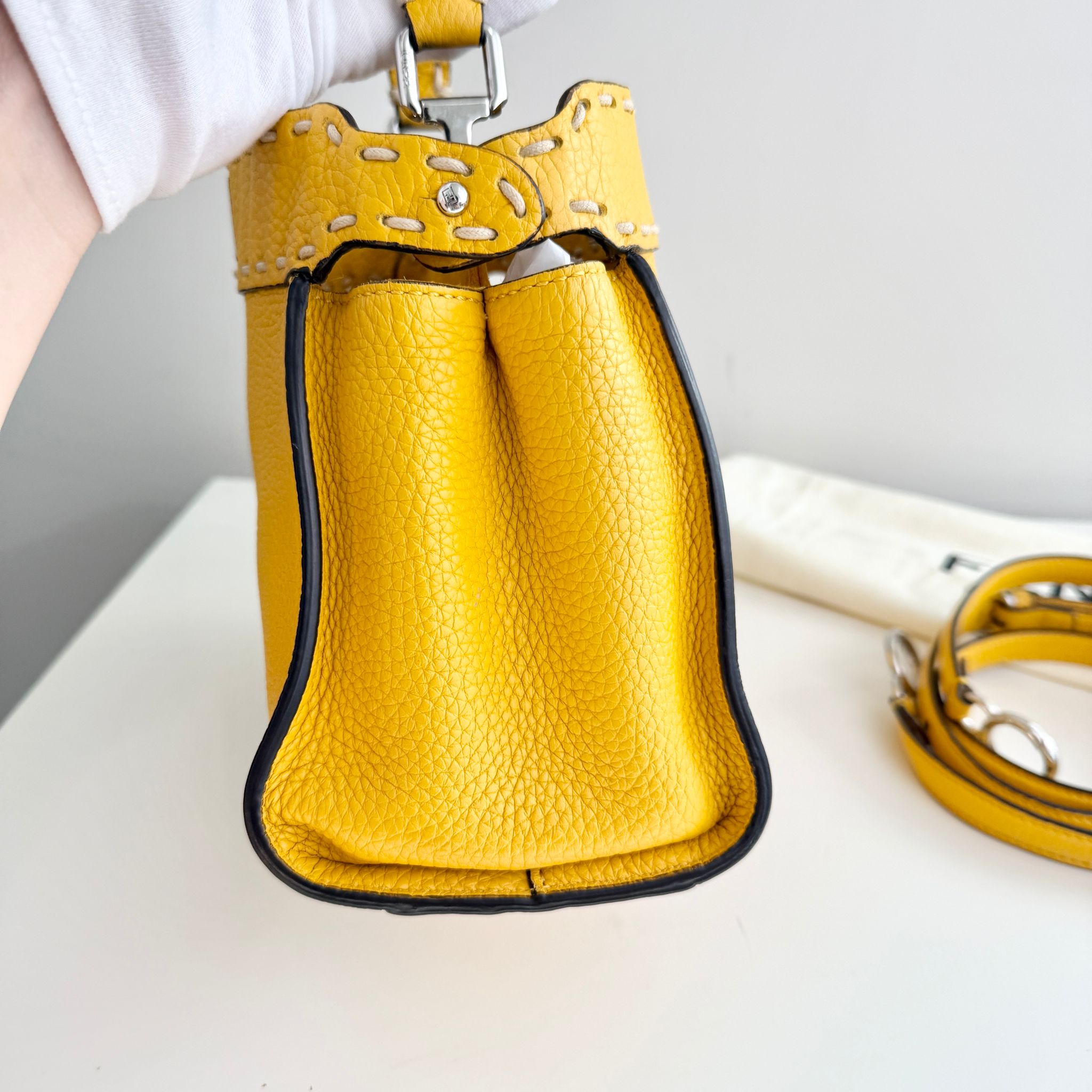 Yellow leather handbag with a strap on a light background