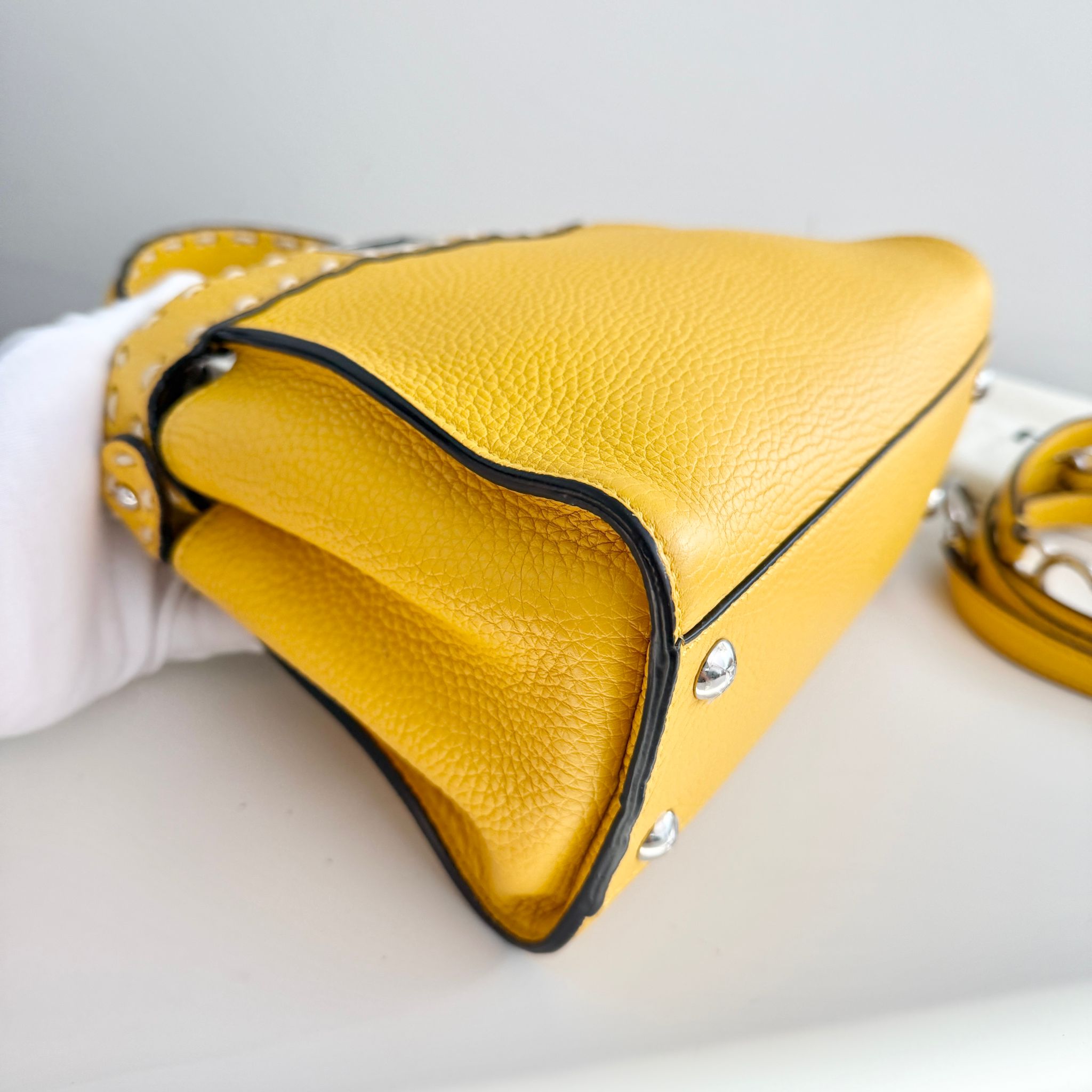 Yellow leather handbag with a strap on a light gray background