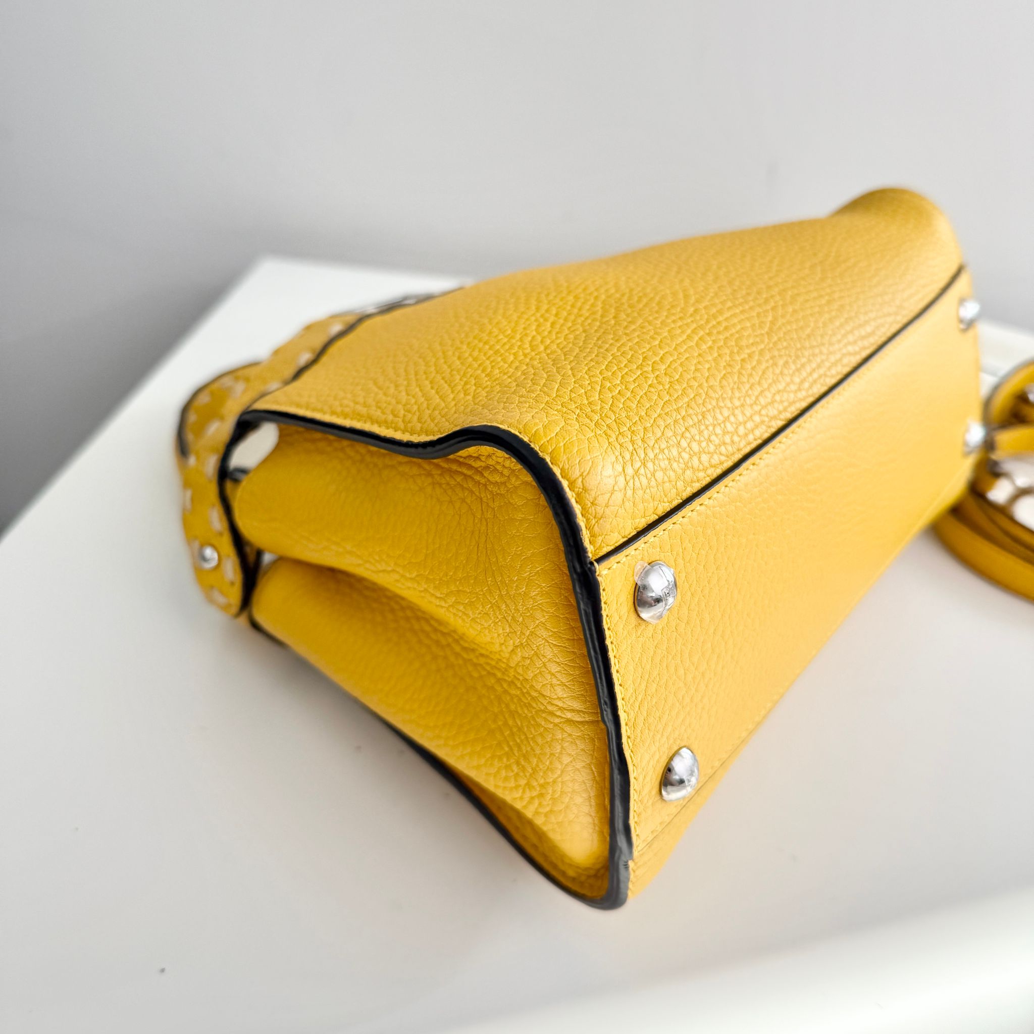 Yellow handbag with silver studs on a white surface