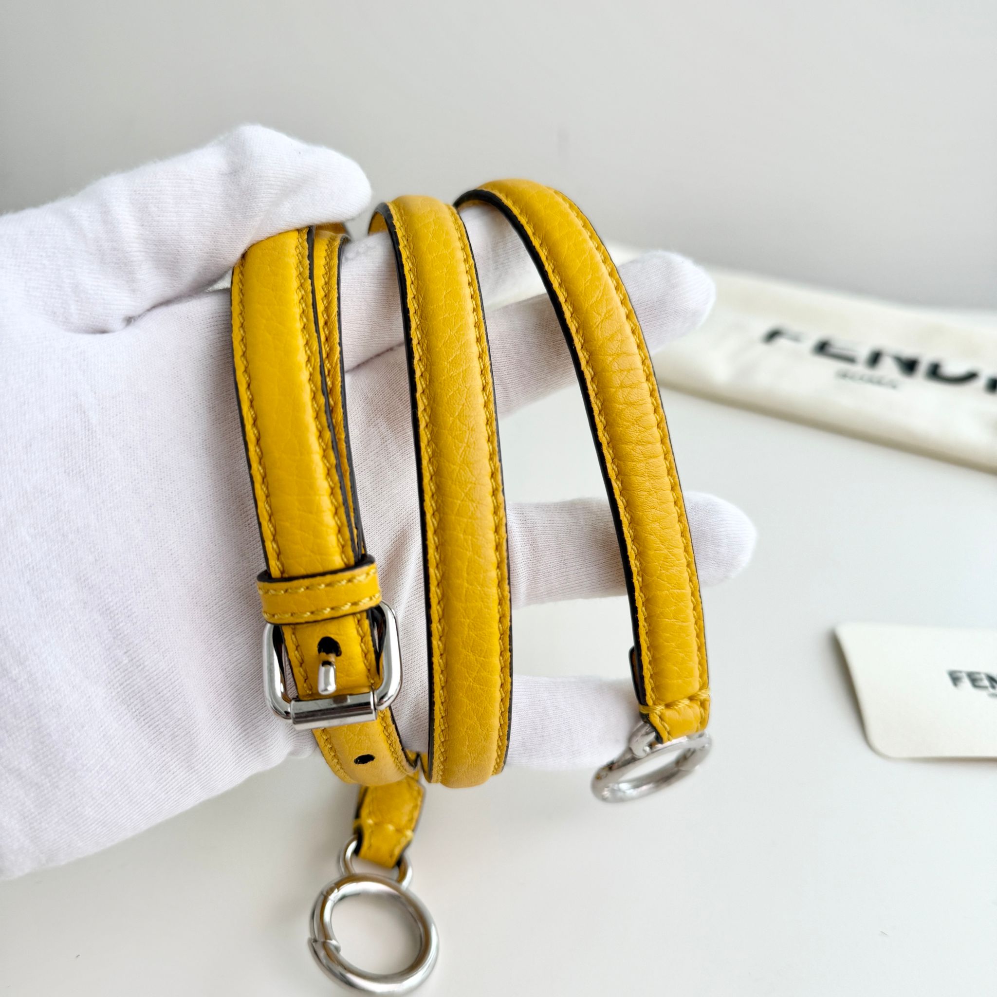Yellow leather dog collar with a metal buckle on a white background