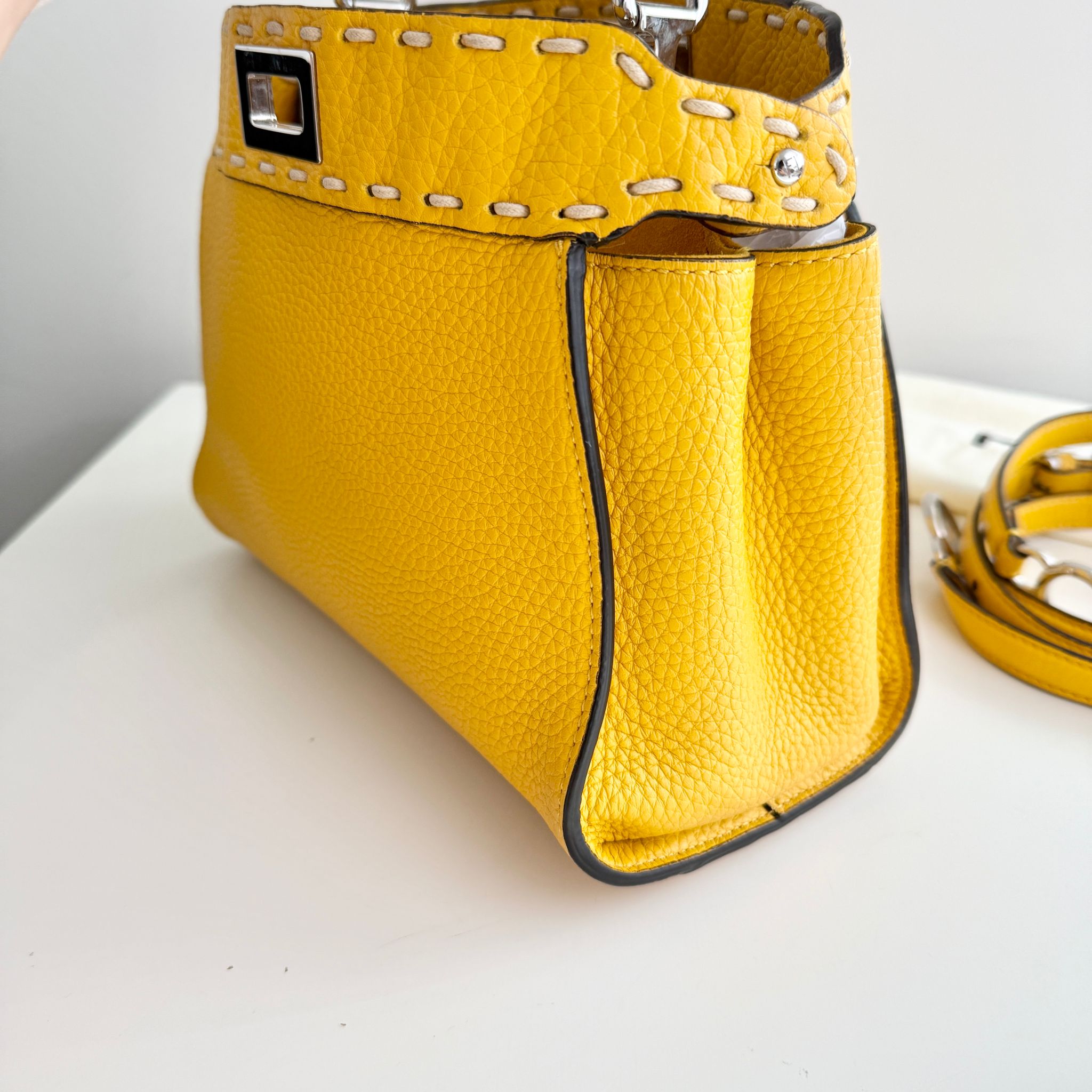 Yellow handbag with a strap on a white surface