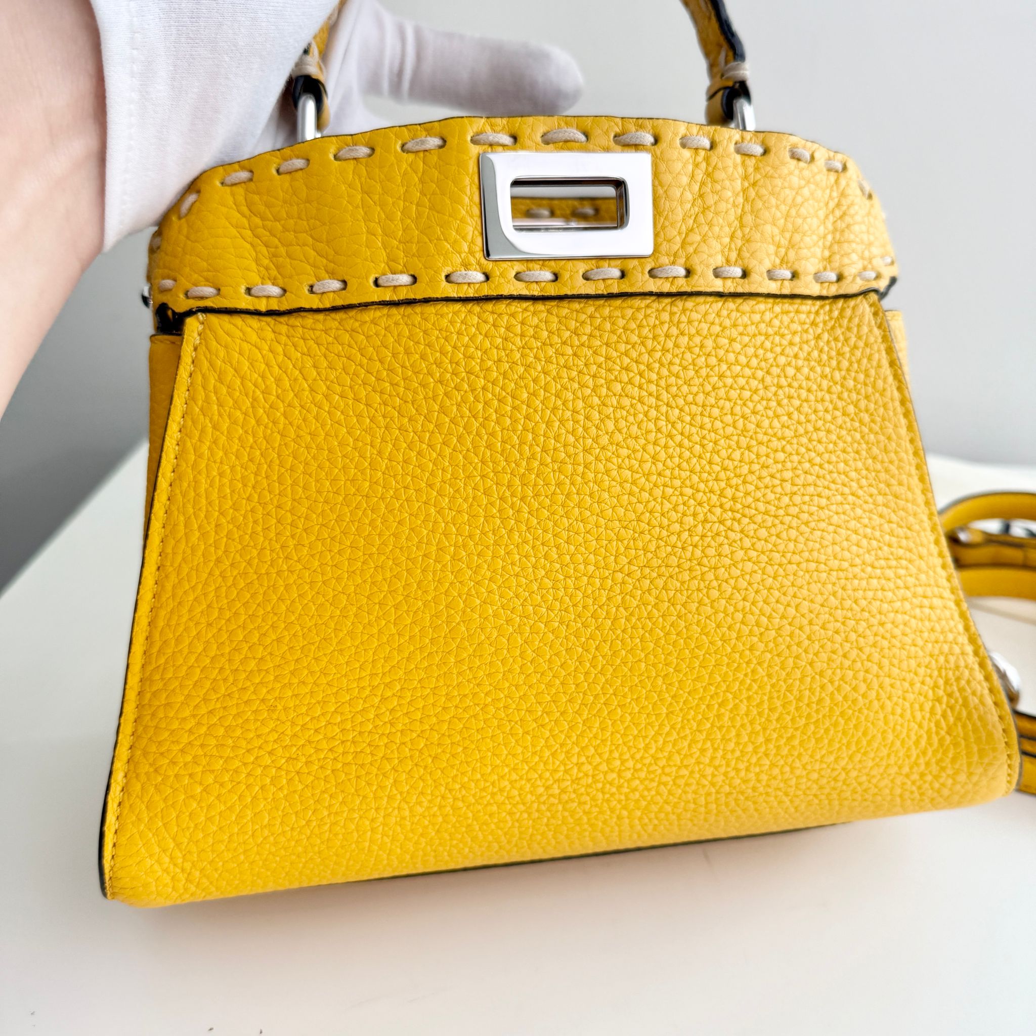 Yellow handbag with a silver clasp on a light background