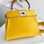将图片加载到图库查看器，Yellow handbag with gold accents held by a gloved hand on a light gray background
