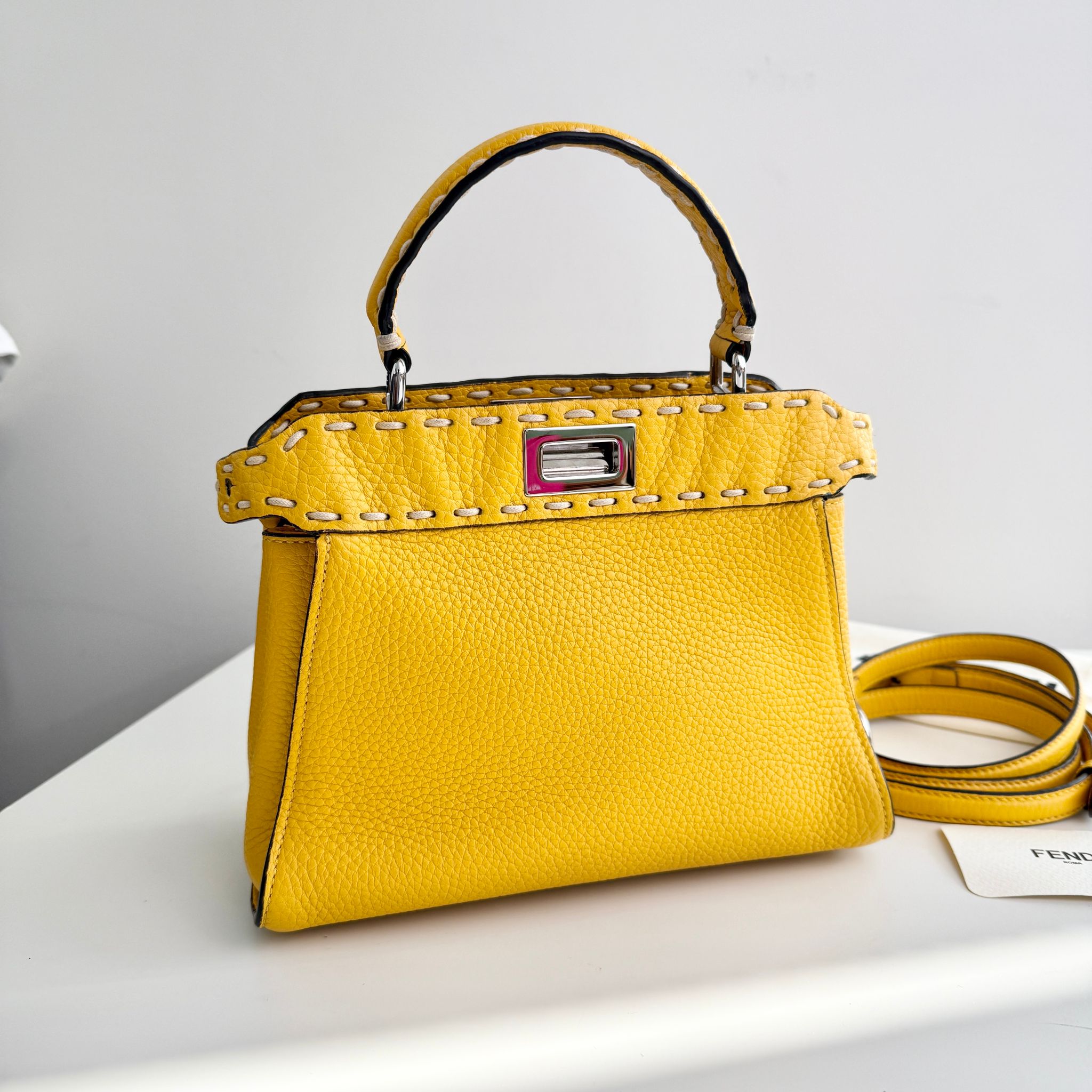 Yellow handbag with studded details on a white surface