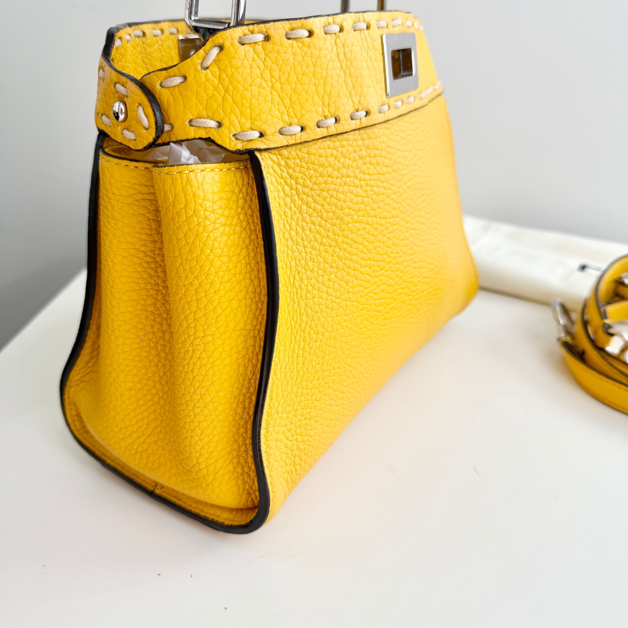 Yellow handbag with studded detail on a white surface