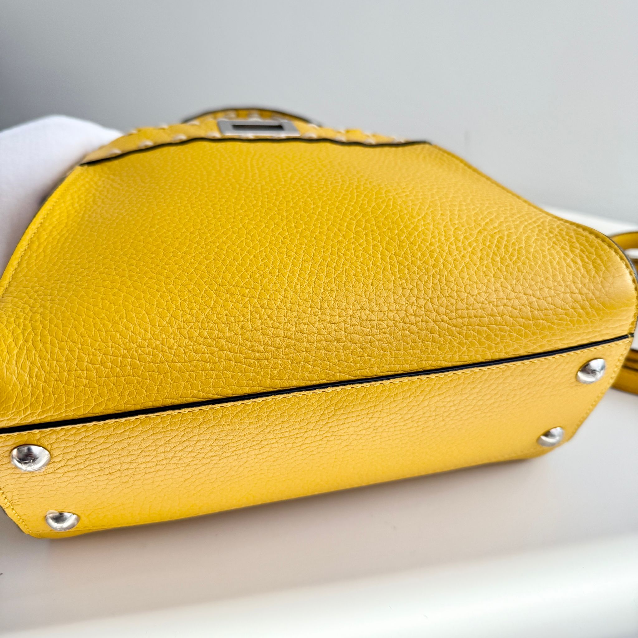 Yellow handbag with silver studs on a light gray background