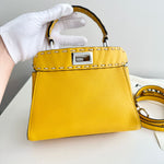 将图片加载到图库查看器，Yellow handbag with gold accents held by a gloved hand on a light background
