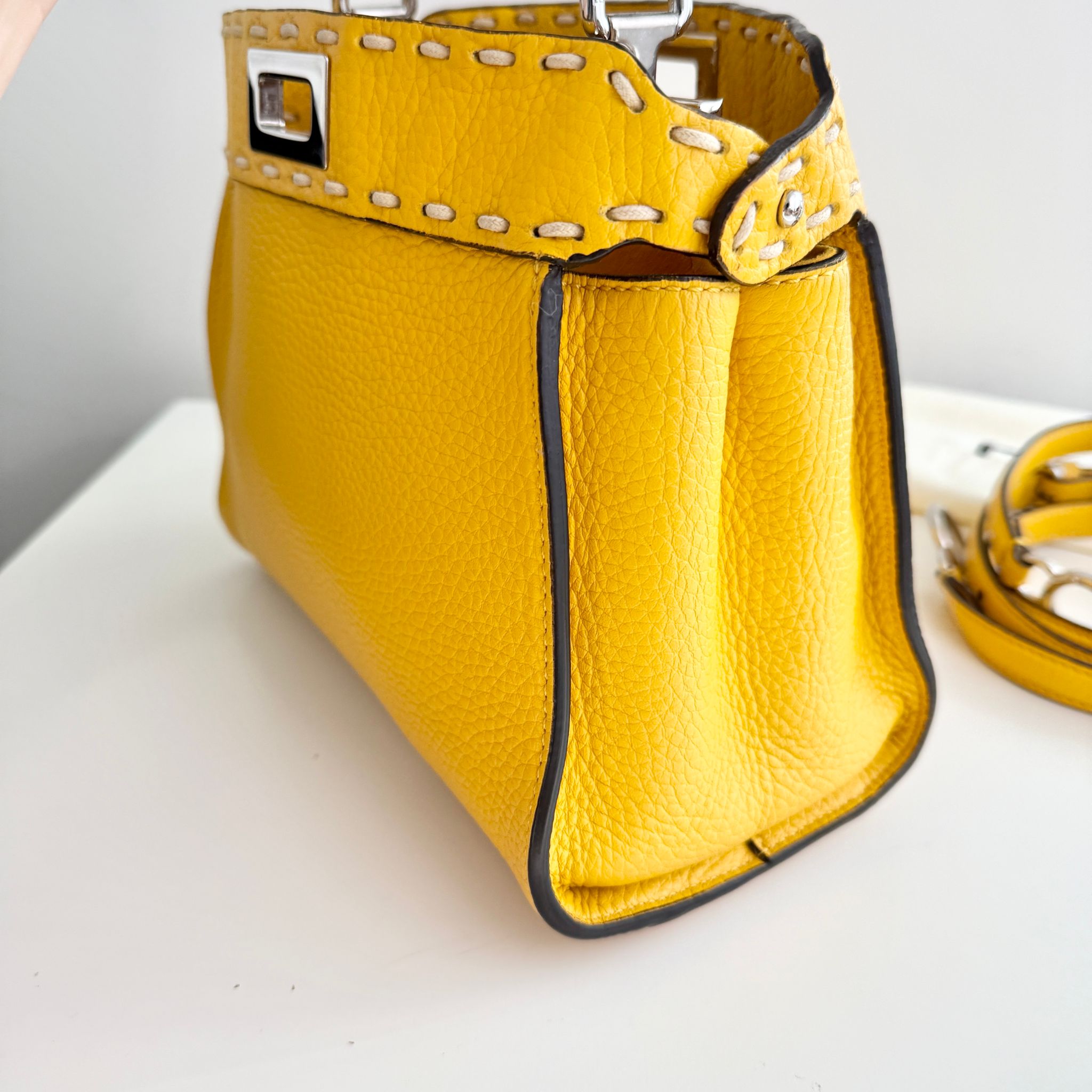 Yellow handbag with studded details on a white surface