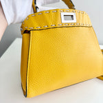 将图片加载到图库查看器，Yellow handbag with a textured surface and visible brand logo on a light background
