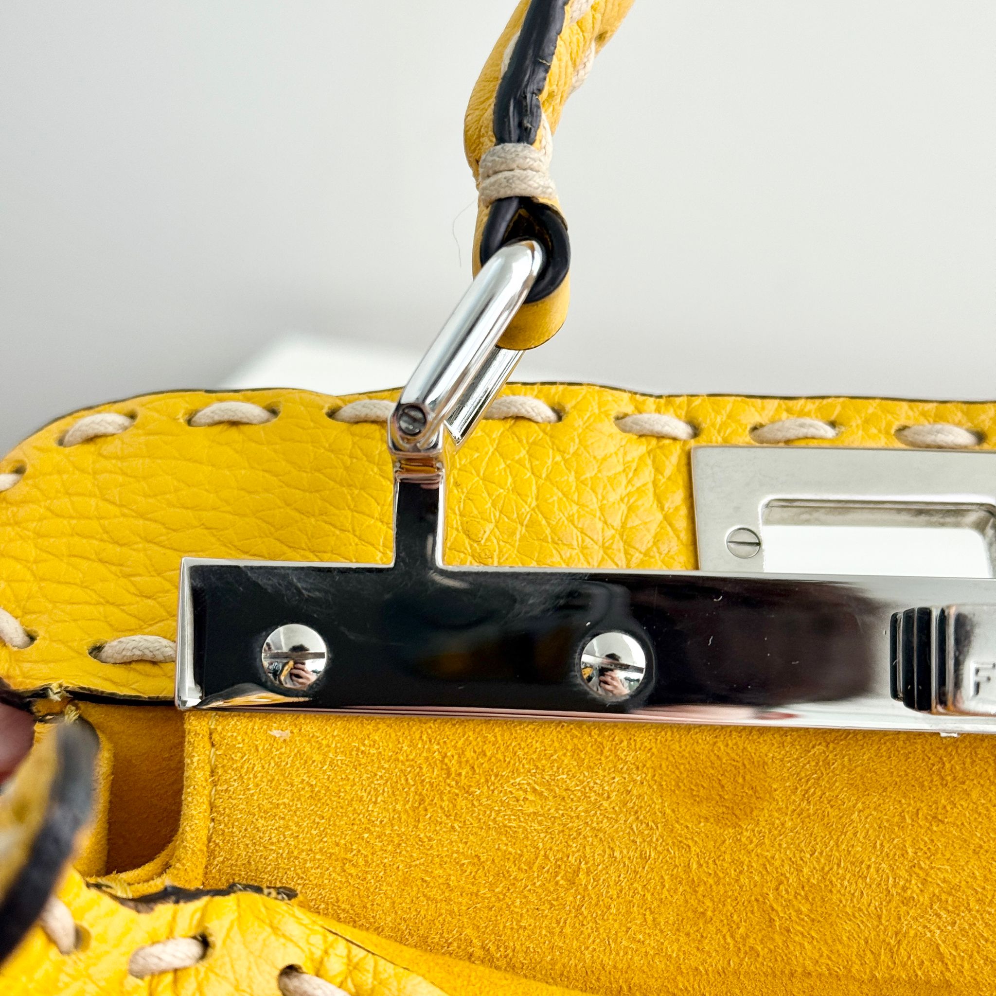 Close-up of a yellow handbag with metal hardware on a white background
