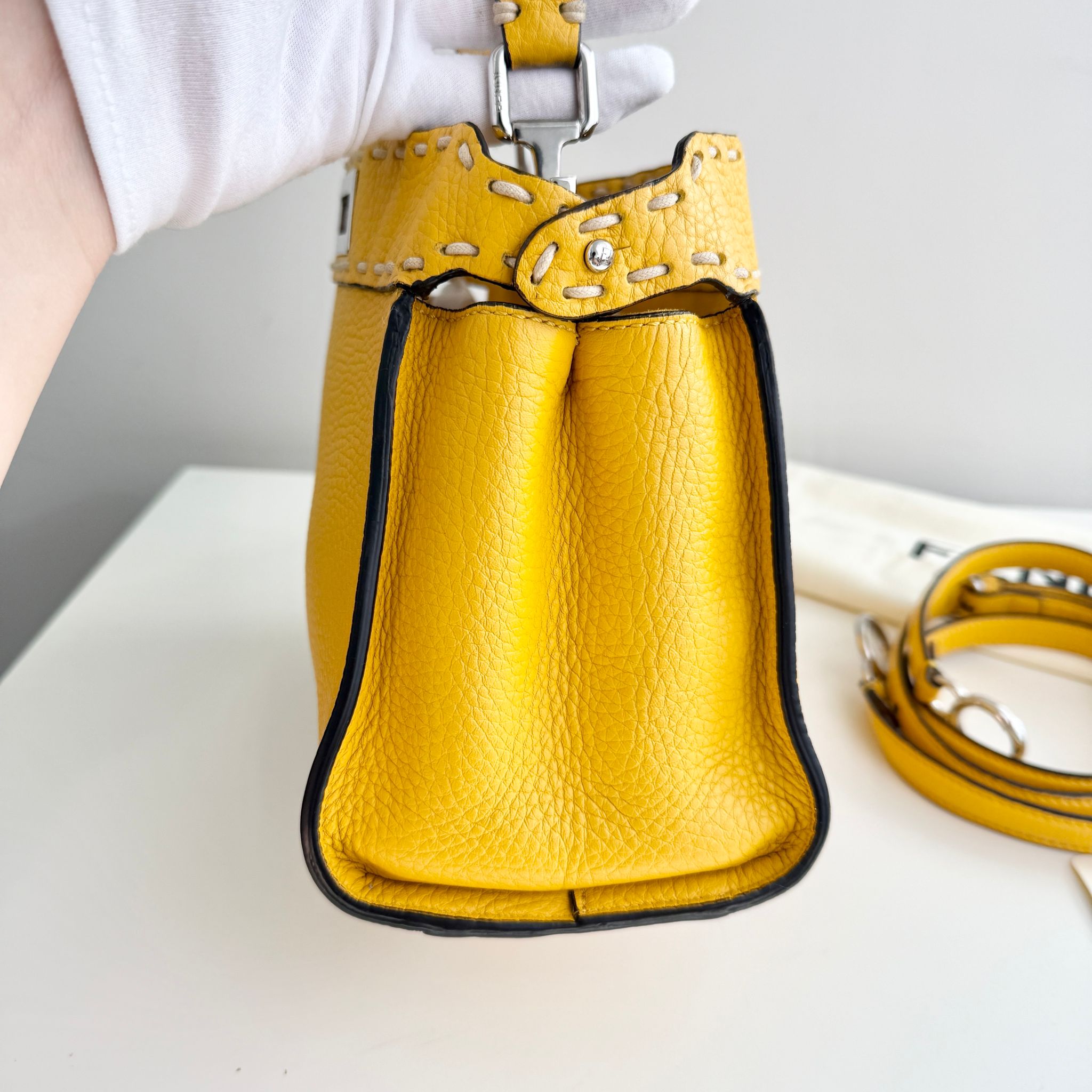 Yellow leather handbag with a strap on a light background