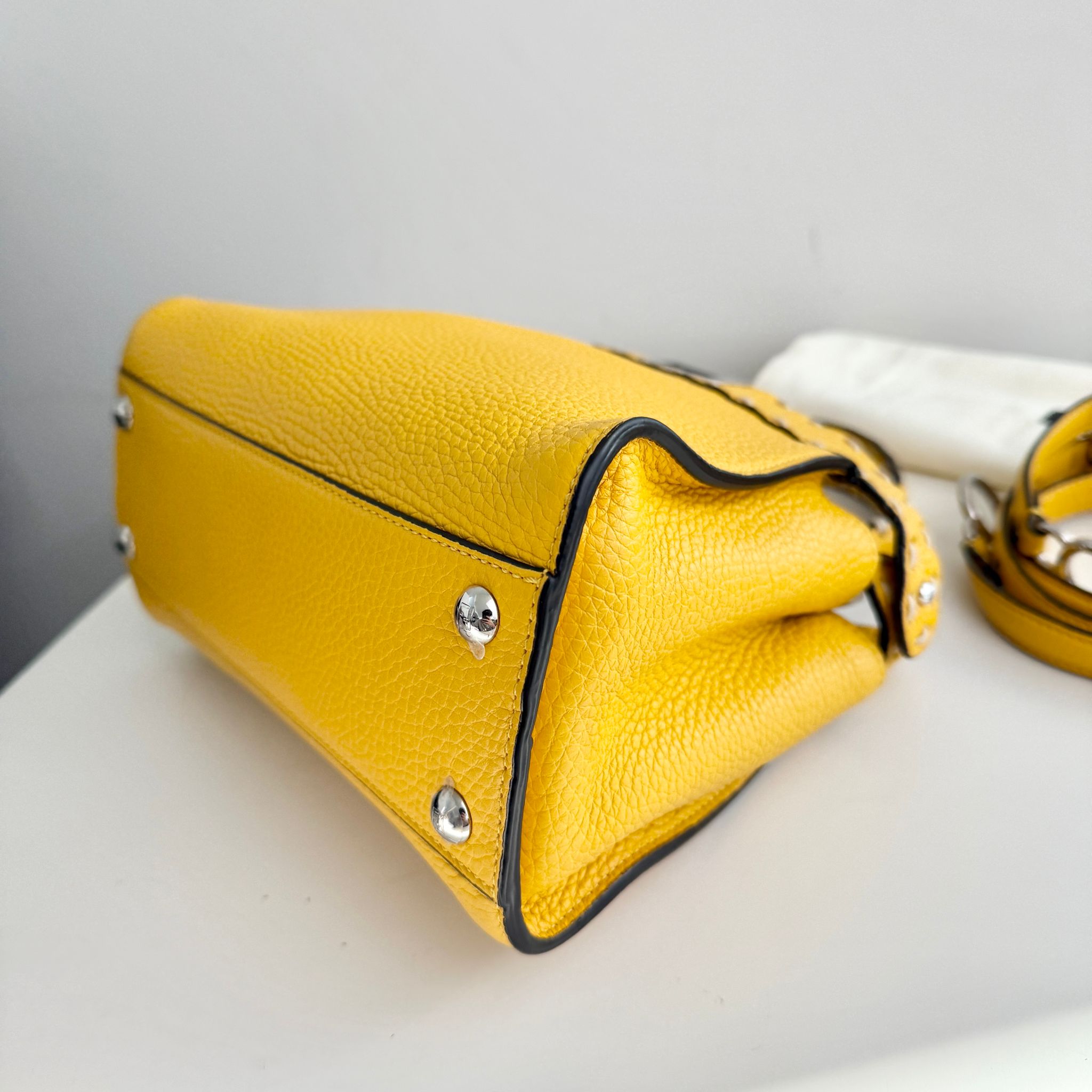Yellow handbag with black trim on a white surface