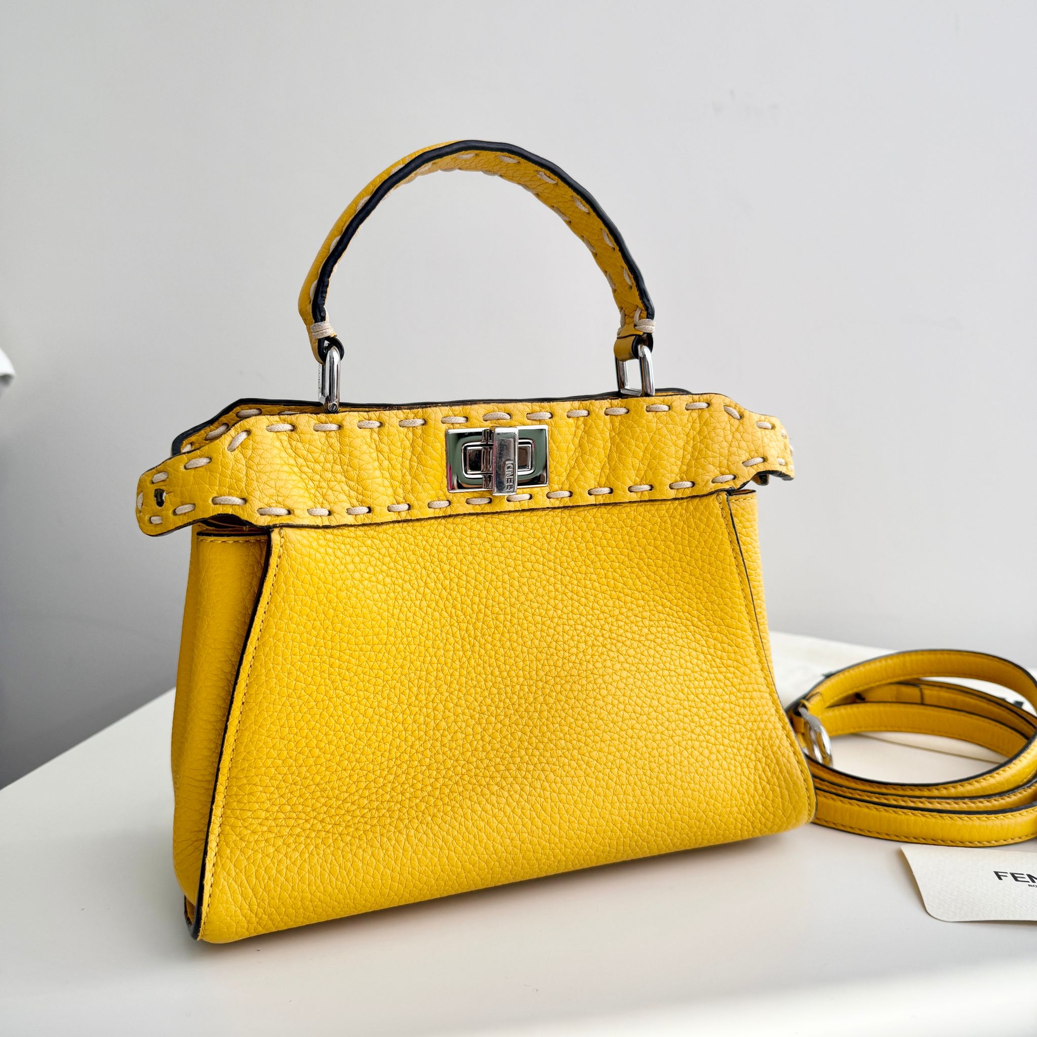 Yellow handbag with studded detail on a white surface
