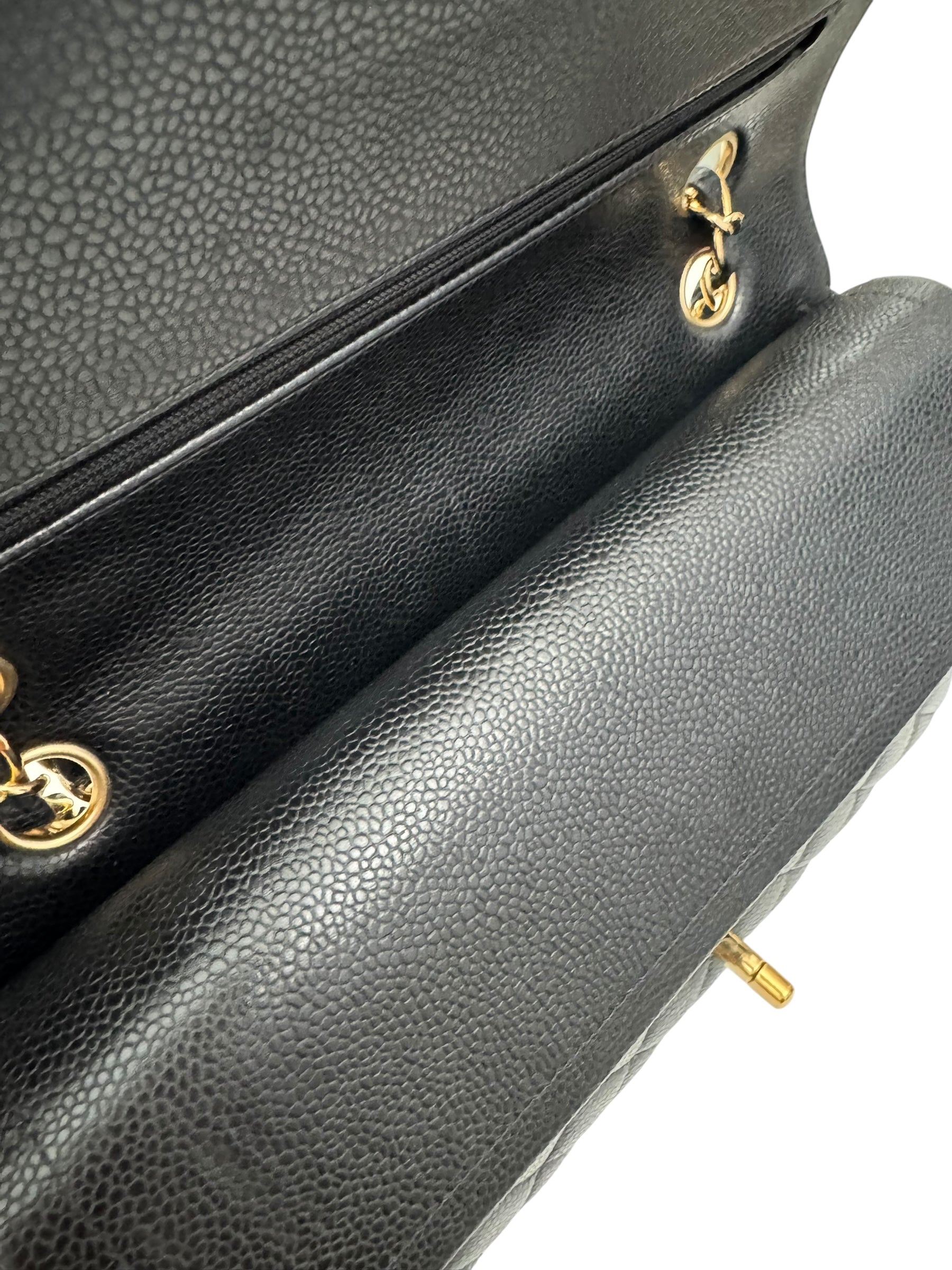 Close-up of a black leather handbag with gold hardware on a white background