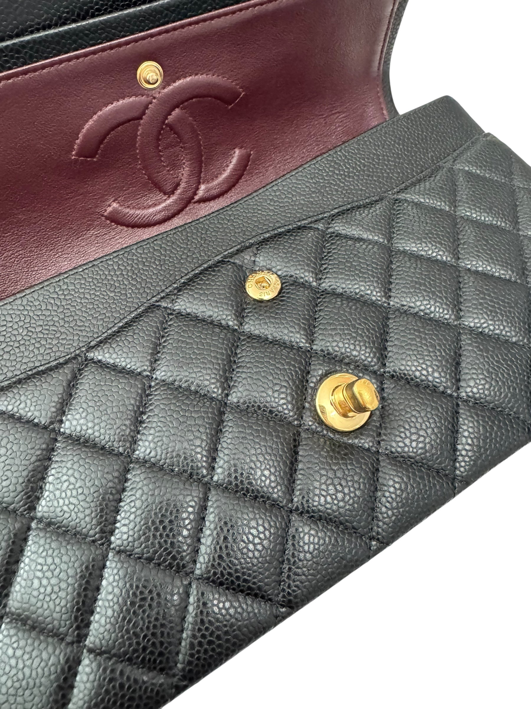 Close-up of a Chanel handbag with quilted black leather and gold hardware.