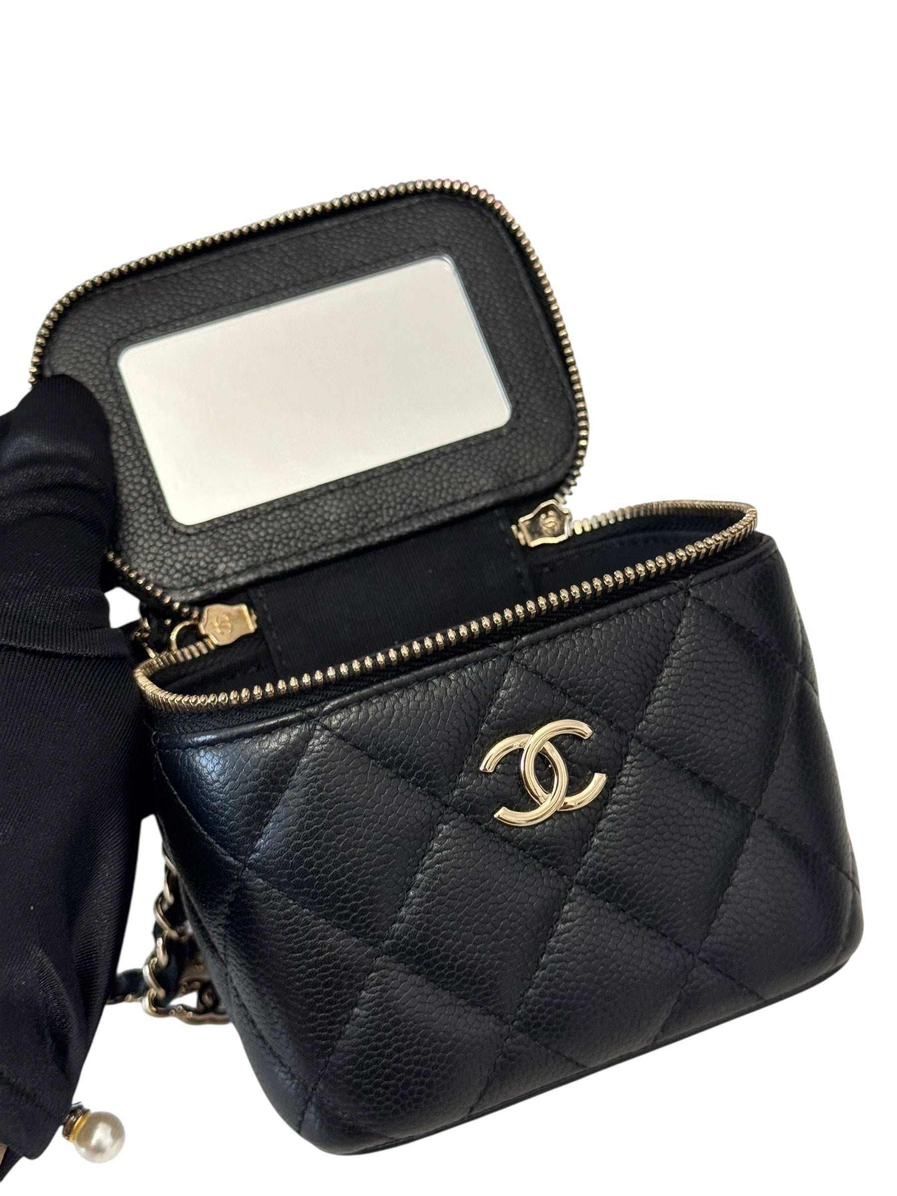 Black quilted handbag with gold hardware on a white background