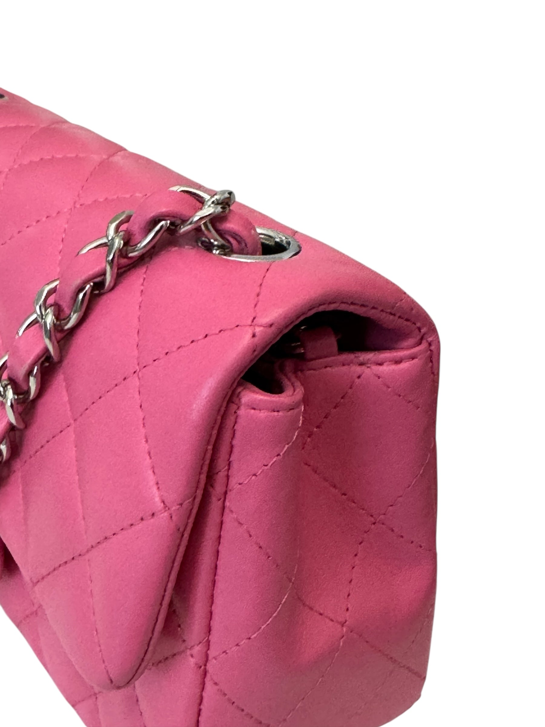 Close-up of a pink quilted handbag with a silver chain detail on a white background