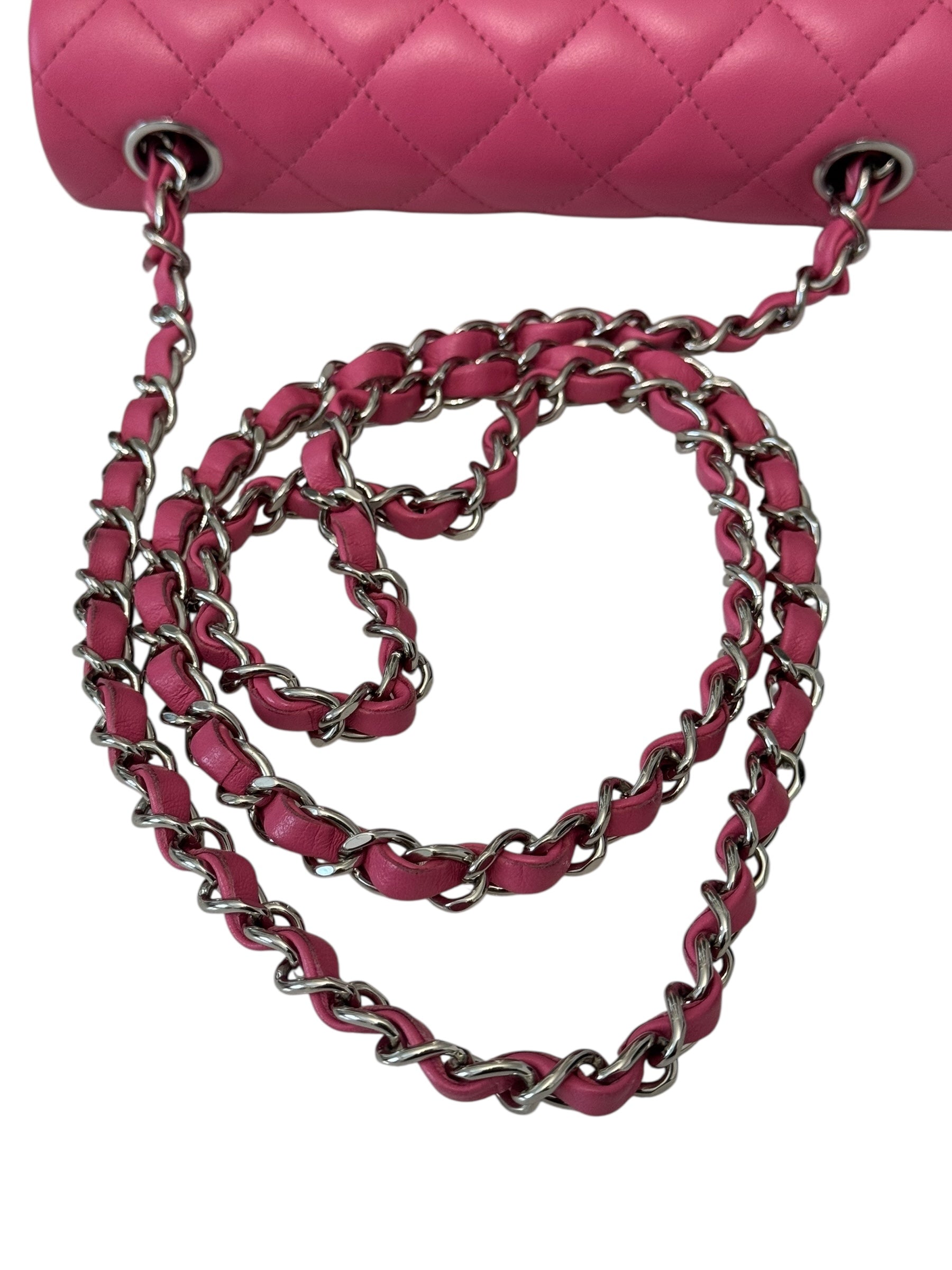 Close-up of a pink quilted handbag with a matching chain strap on a white background