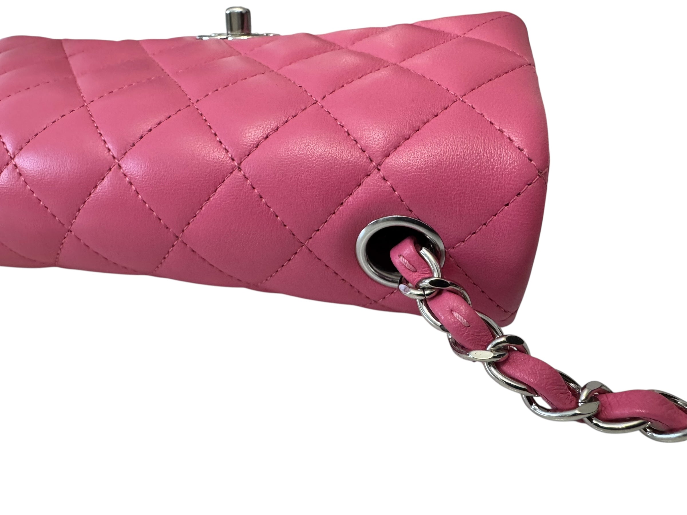 Pink quilted handbag with chain strap on a white background