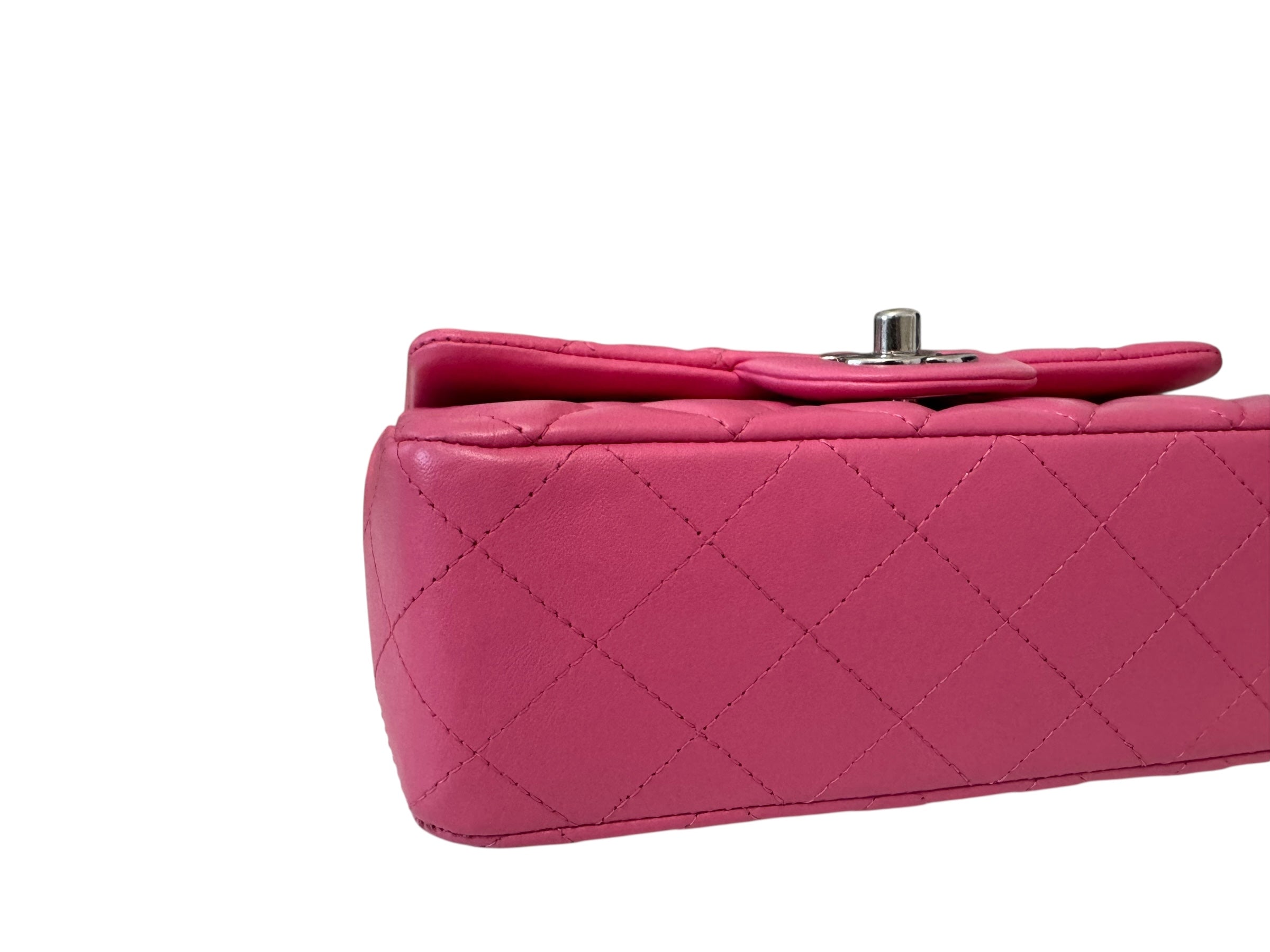 Close-up of a pink quilted handbag with a silver clasp on a white background