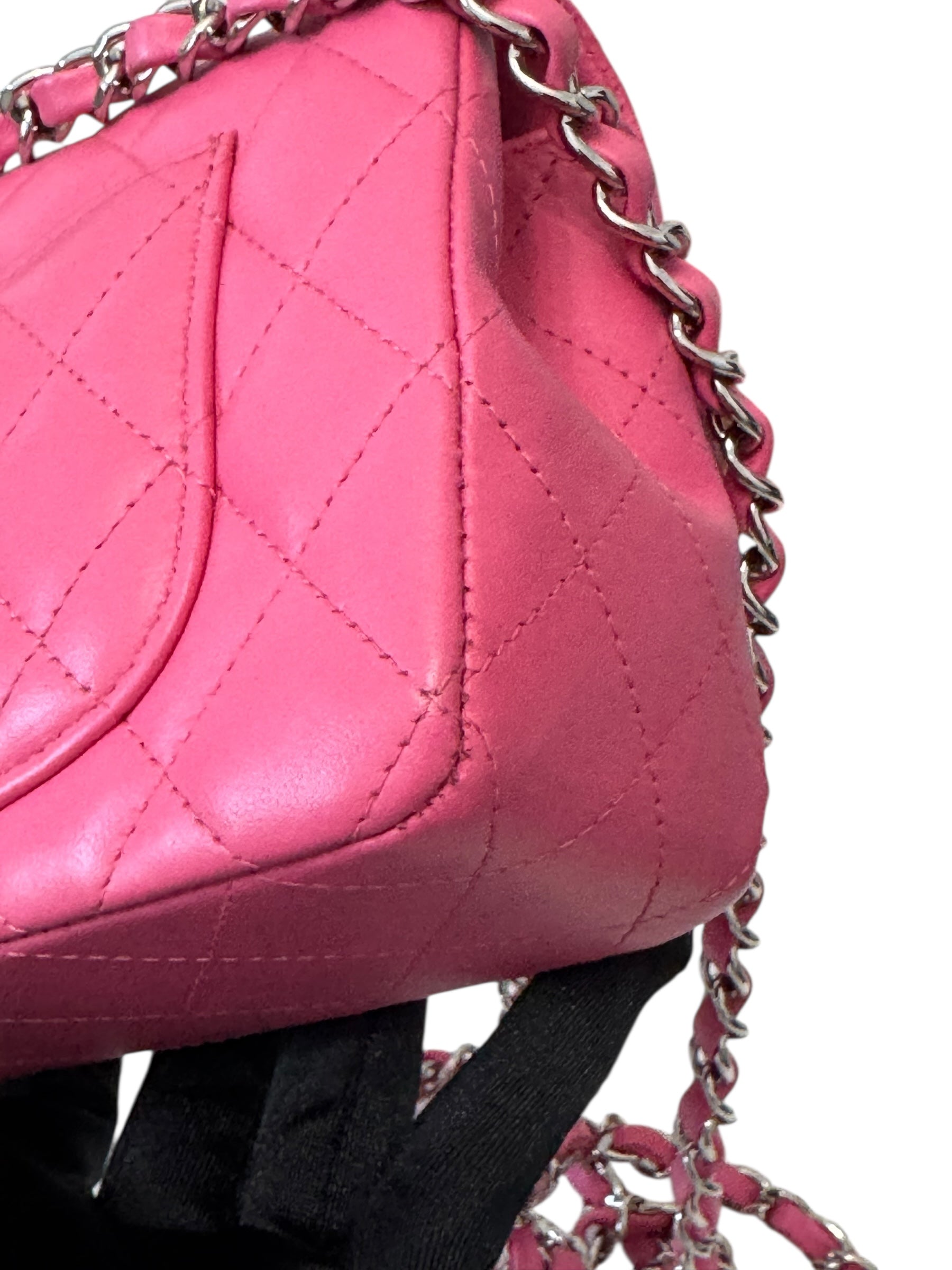 Close-up of a pink quilted handbag with a chain strap on a white background