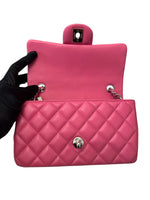 将图片加载到图库查看器，Pink quilted handbag with a black glove holding it on a white background
