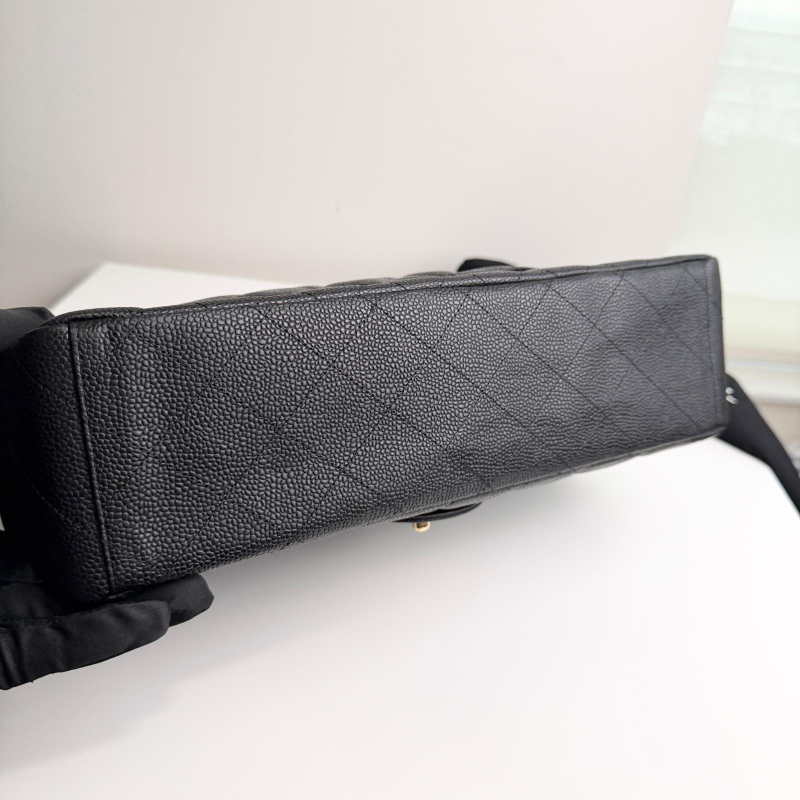Black textured handbag held by a gloved hand on a white surface
