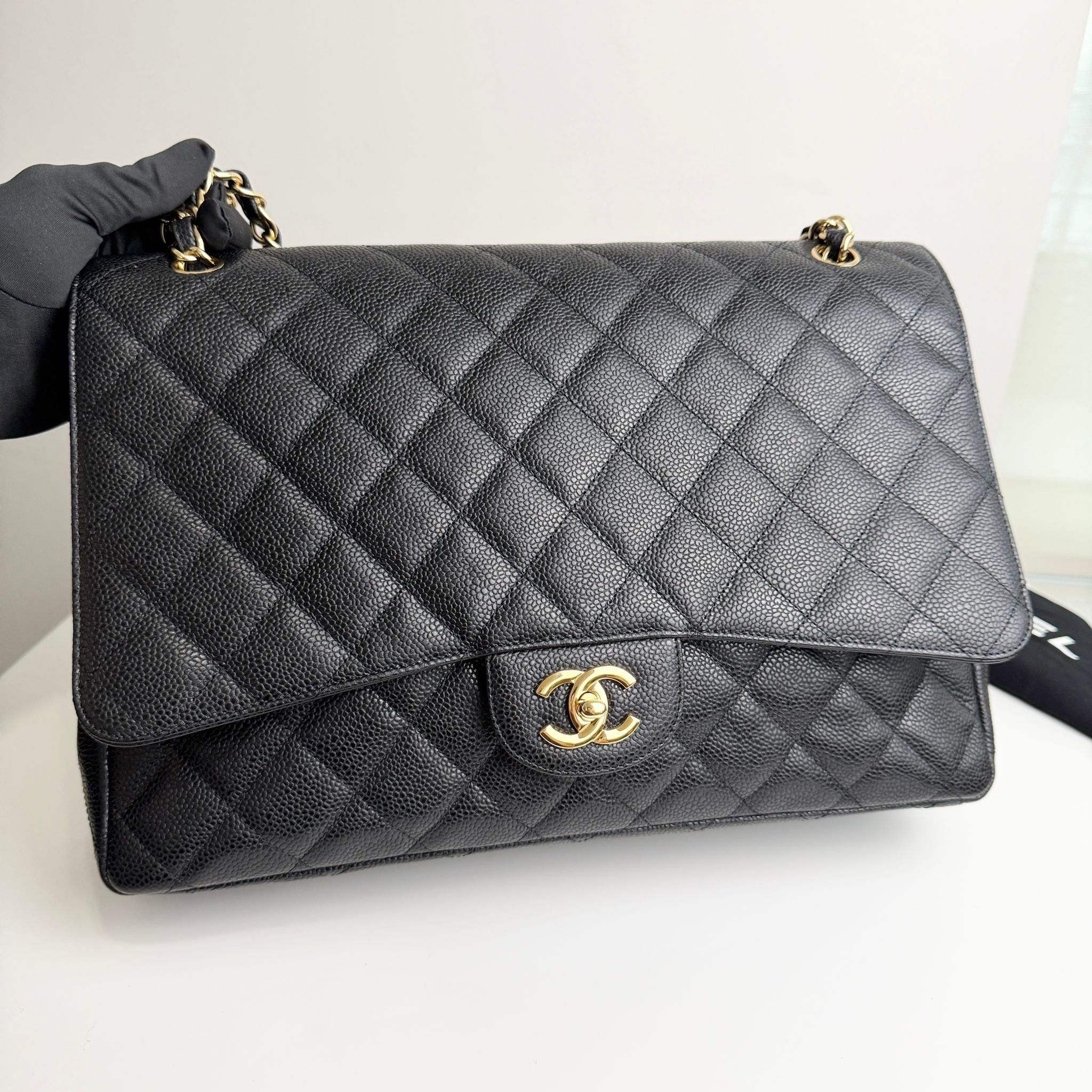 Quilted black handbag with gold hardware on a white background