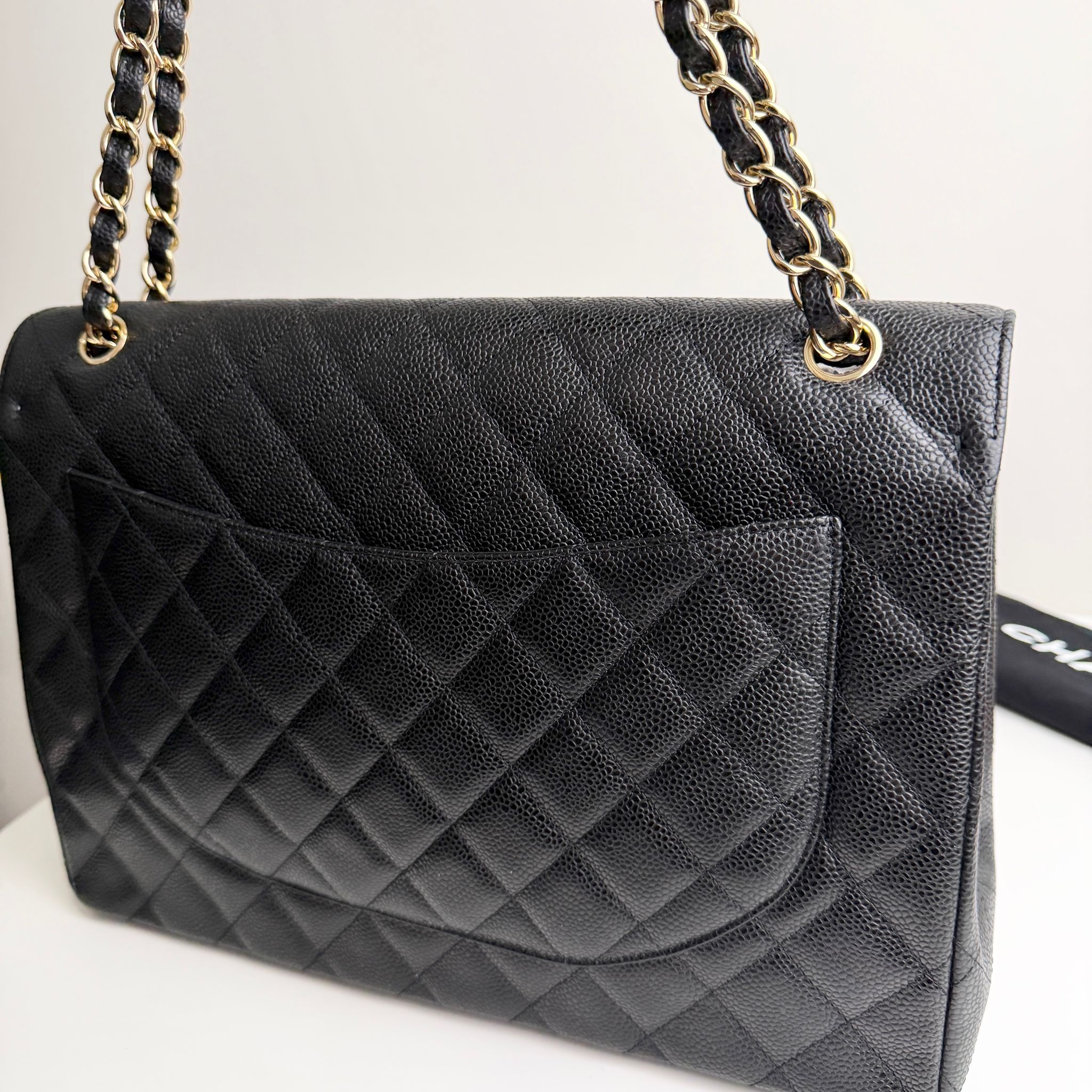 Black quilted handbag with gold chain strap on a white background