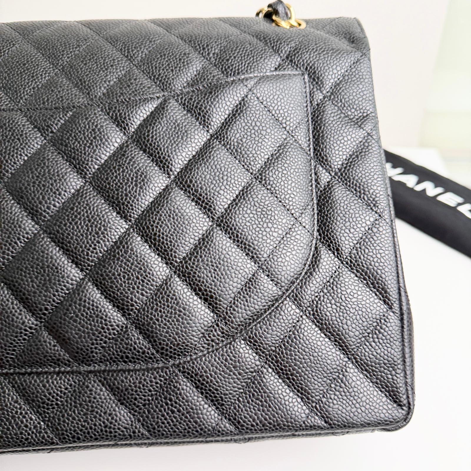 Black quilted handbag with gold hardware on a white background