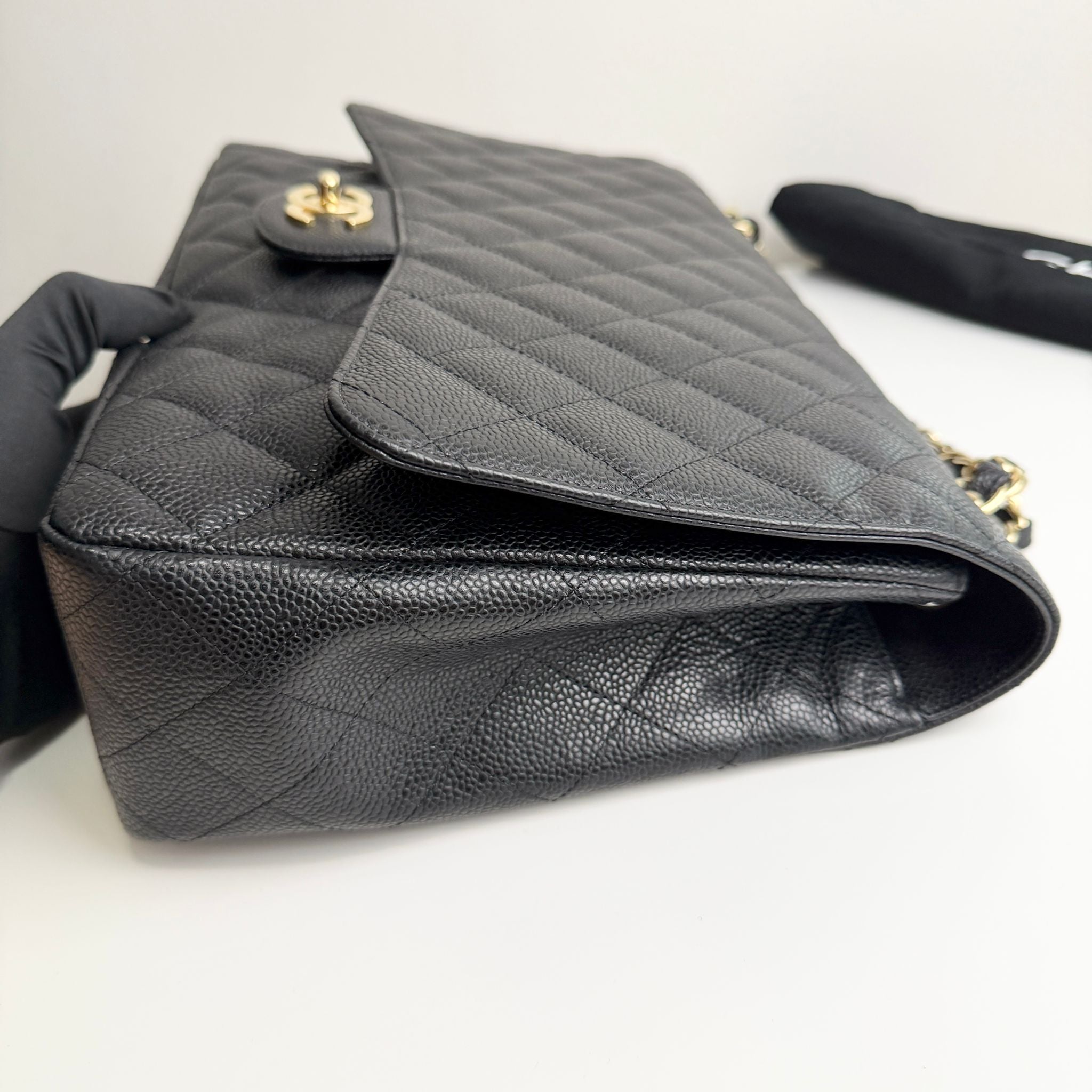 Black quilted handbag with gold hardware on a white surface