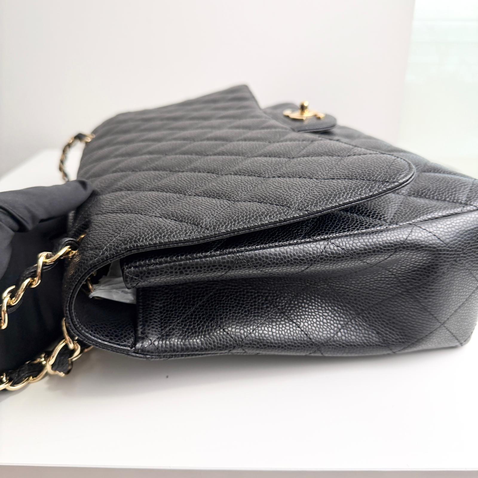 Black quilted handbag with gold chain on a white background