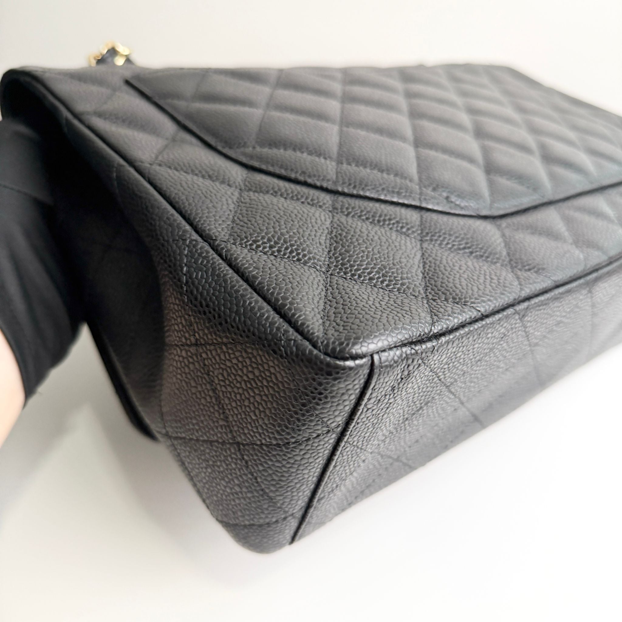 Black quilted handbag on a white background