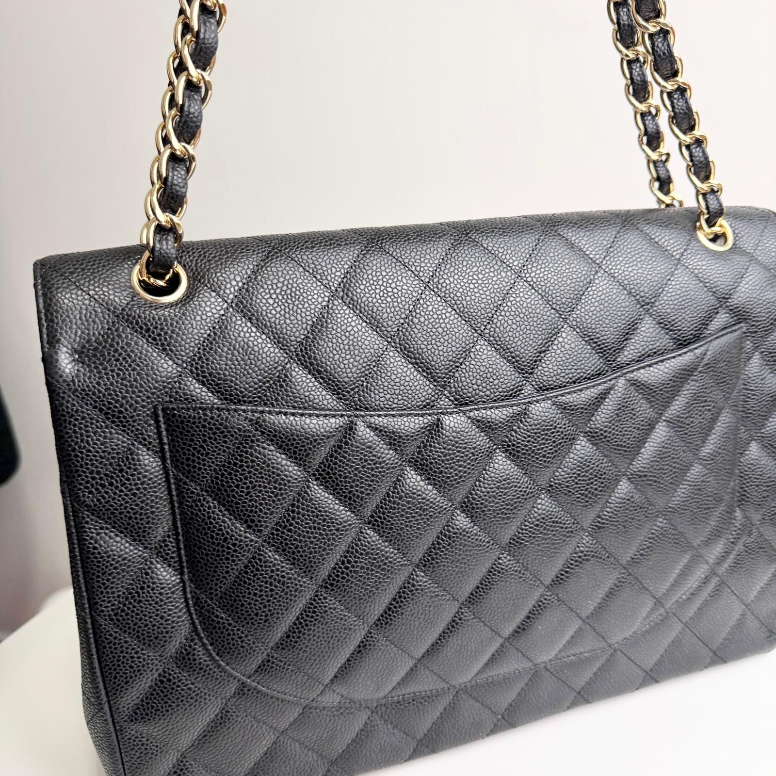 Quilted black handbag with gold chain strap on a light background