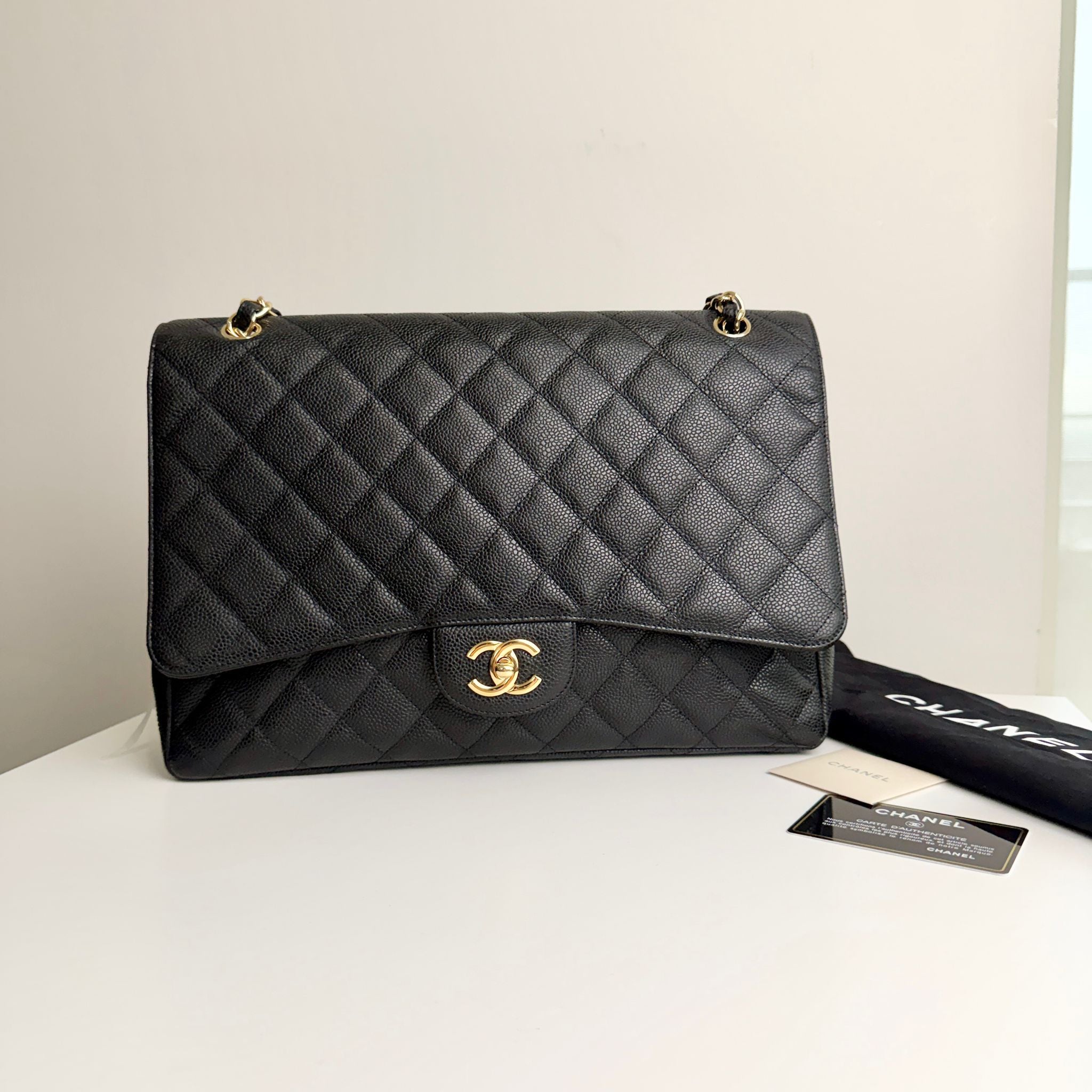 Black quilted handbag with gold hardware on a white surface, featuring the Chanel logo.