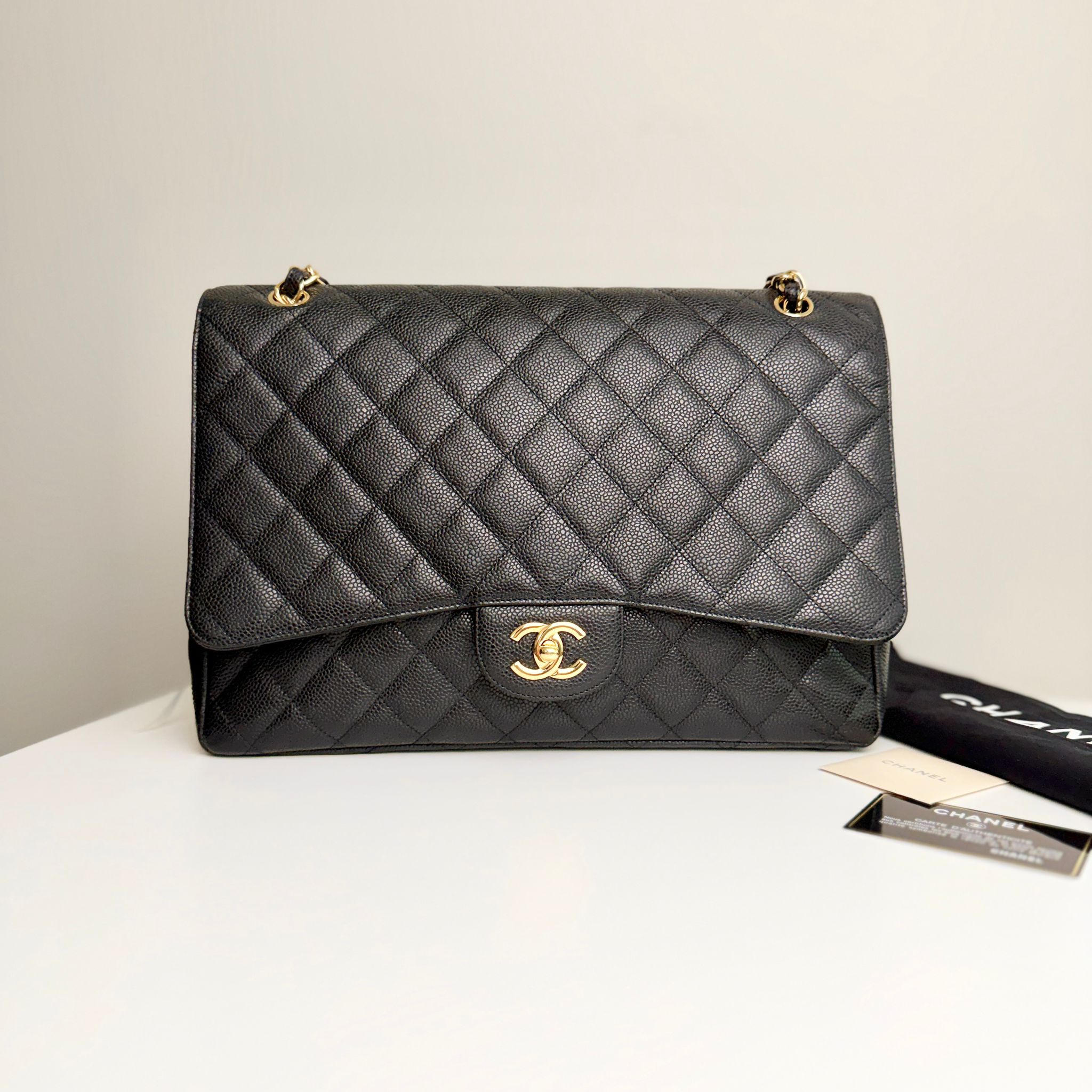 Black quilted Chanel handbag on a white surface with a beige background