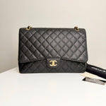 将图片加载到图库查看器，Black quilted Chanel handbag on a white surface with a beige background
