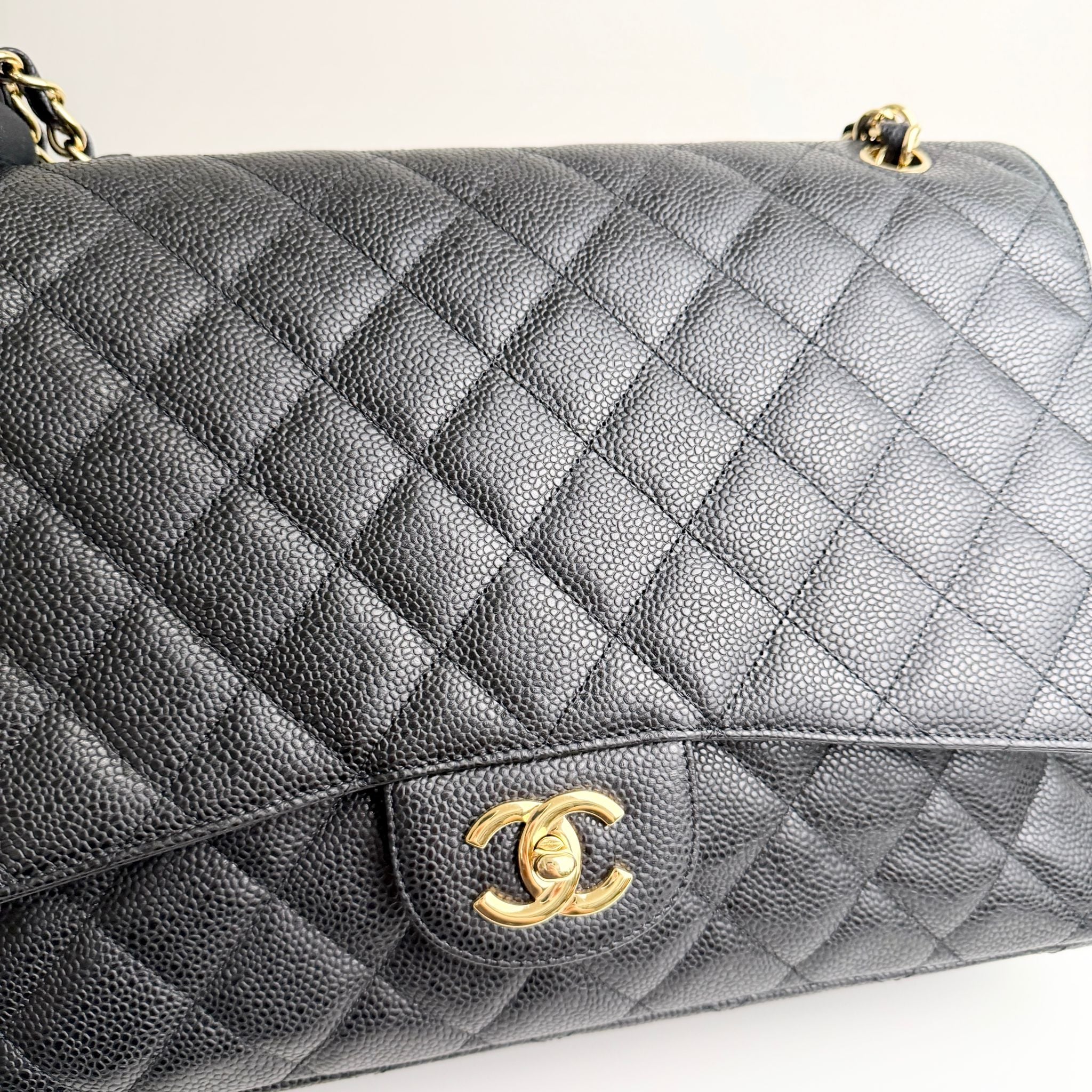 Gray quilted handbag with gold Chanel logo on a white background