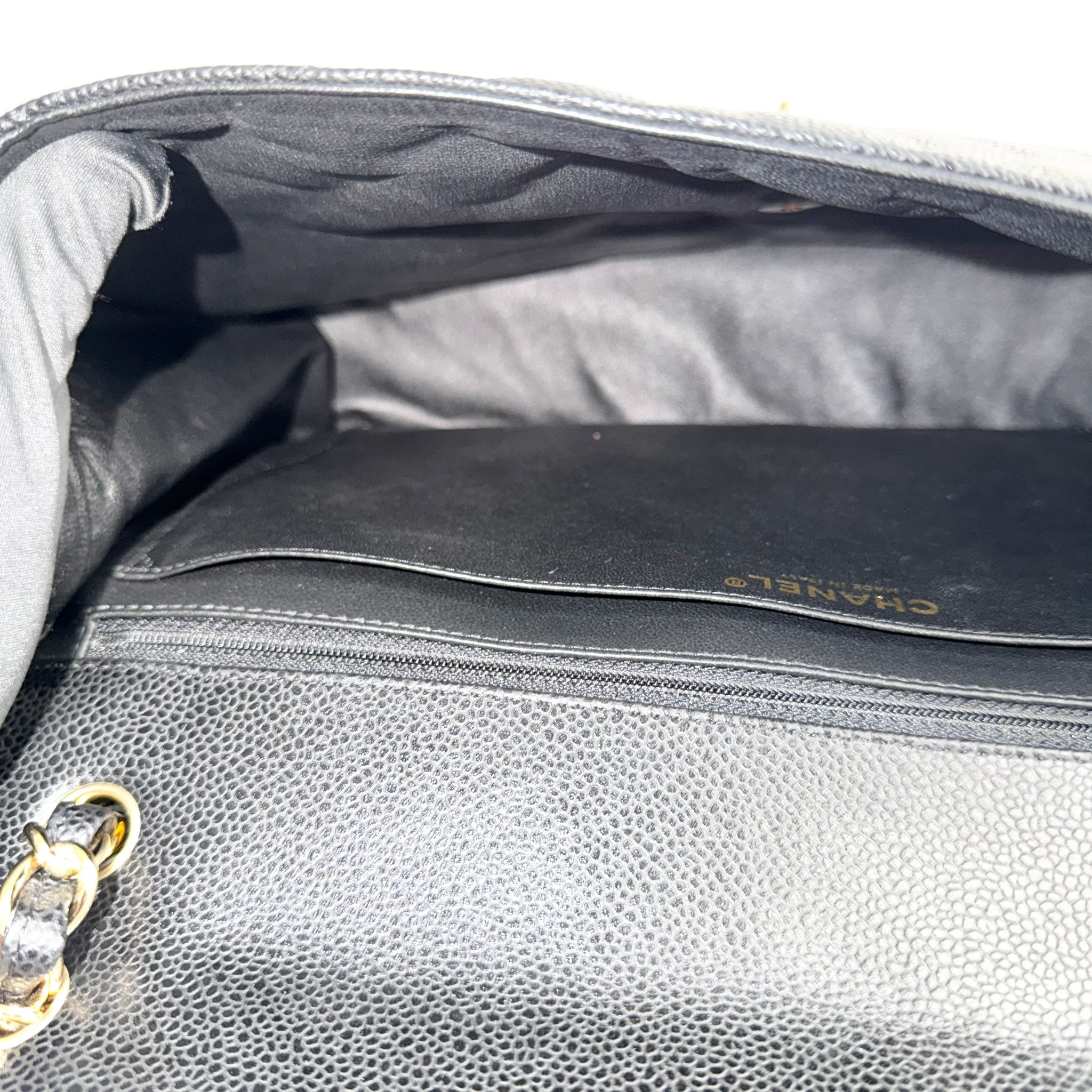 Close-up of a gray handbag with 'Chanel' branding, showing the interior and texture.